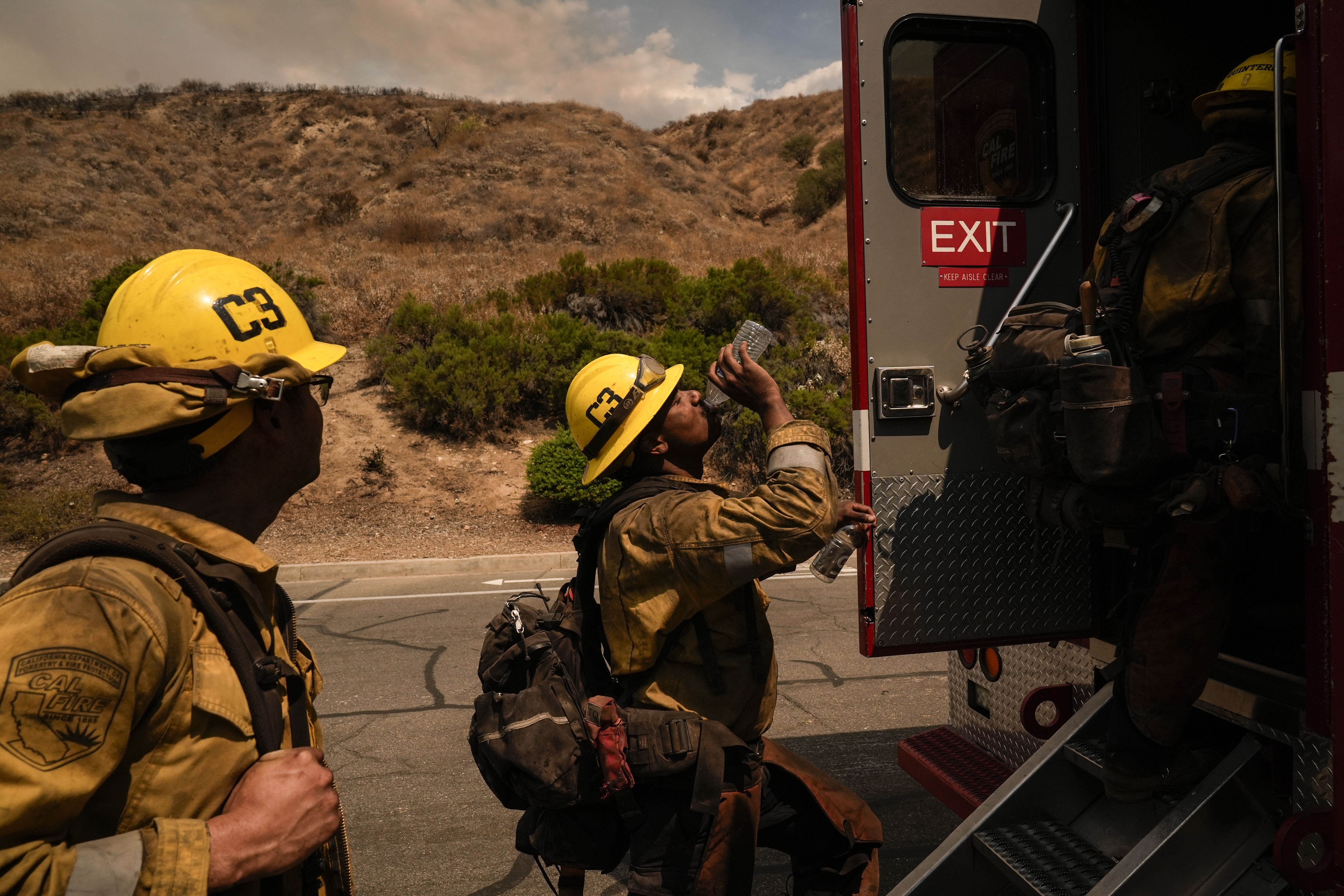 FILE - Firefighter Geo Mulongo, center, finishes his water while taking a break during the Line Fire in Highland, Calif., Sept. 6, 2024. (AP Photo/Jae C. Hong, File)