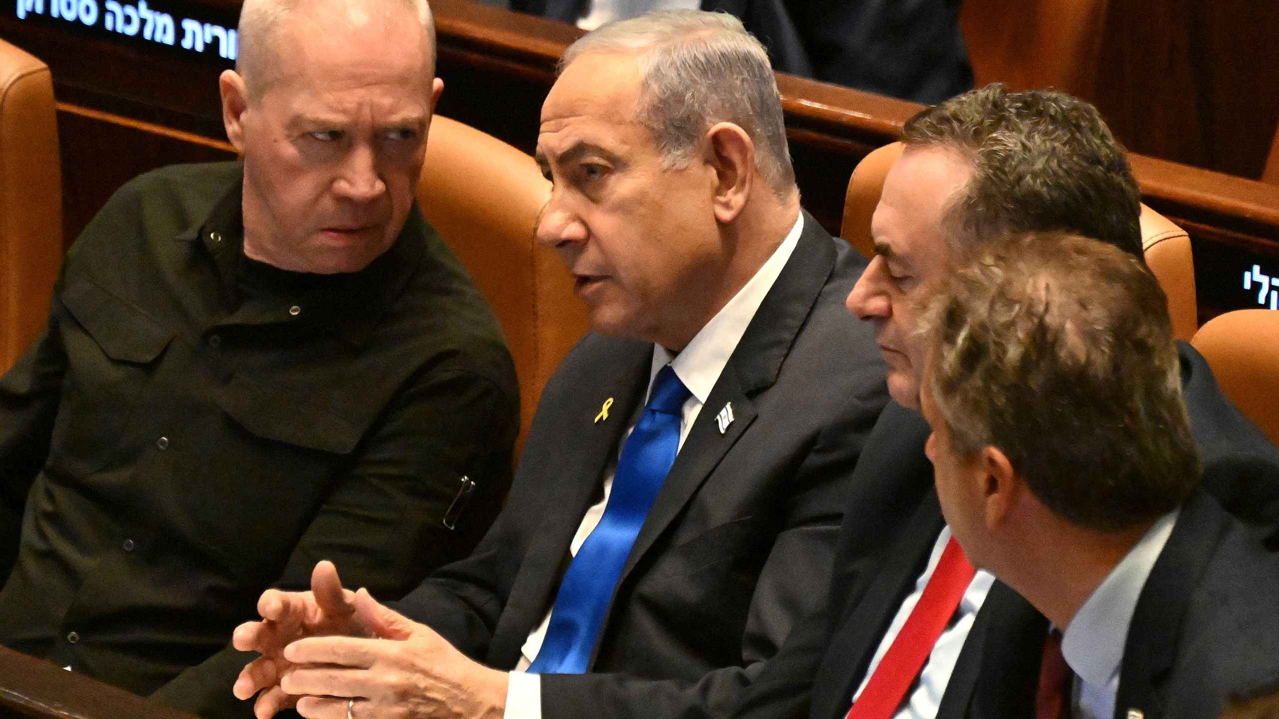 Israeli Prime Minister Benjamin Netanyahu, center, speaks to Defense Minister Yoav Gallant, left, at the opening of the 25th Knesset session marking the anniversary of the "Iron Swords" war, in Jerusalem, Monday, Oct. 28, 2024. (Debbie Hill/Pool Photo via AP)