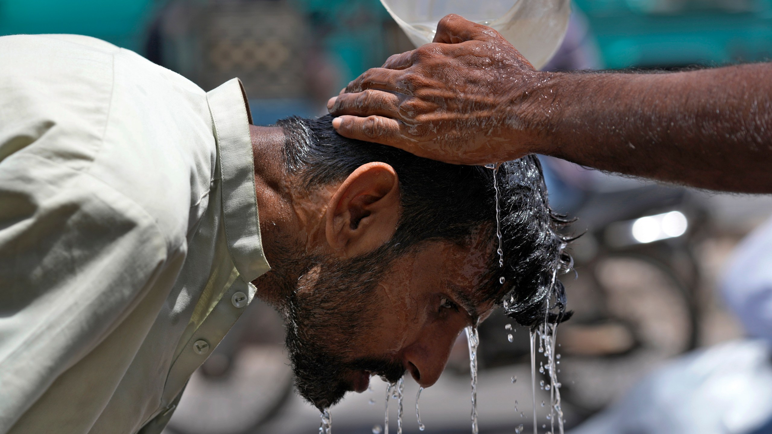 FILE - A volunteer pours water to cool a man off during a hot day in Karachi, Pakistan, May 21, 2024. (AP Photo/Fareed Khan, File)