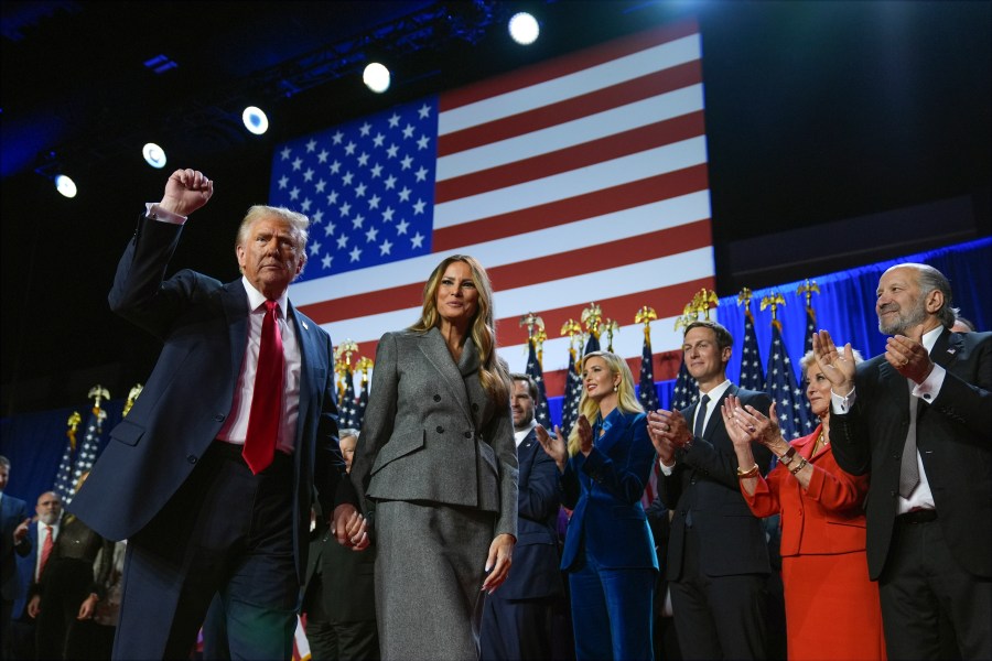 Republican presidential nominee former President Donald Trump gestures as he walks with former first lady Melania Trump at an election night watch party at the Palm Beach Convention Center, Wednesday, Nov. 6, 2024, in West Palm Beach, Fla. (AP Photo/Evan Vucci)