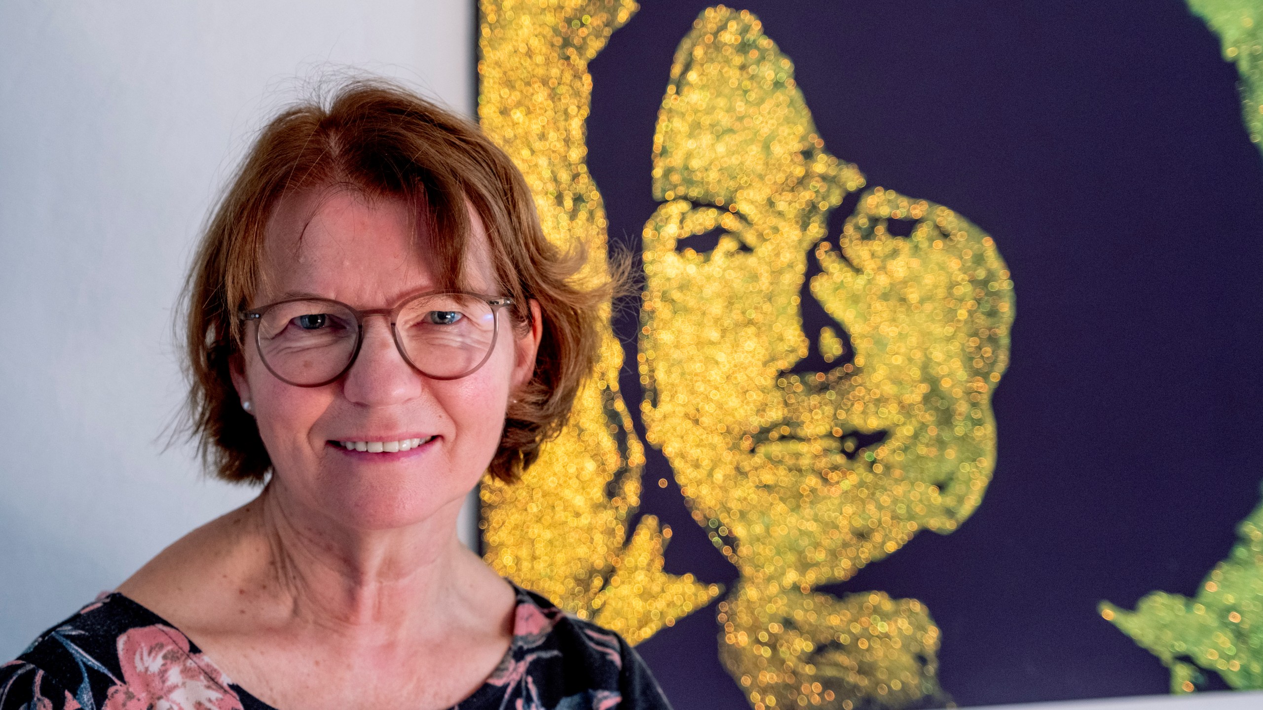 Claudia Huth poses next to a painting showing herself and painted by her son in her house in Egelsbach, Germany, Thursday, Oct. 31, 2024. (AP Photo/Michael Probst)