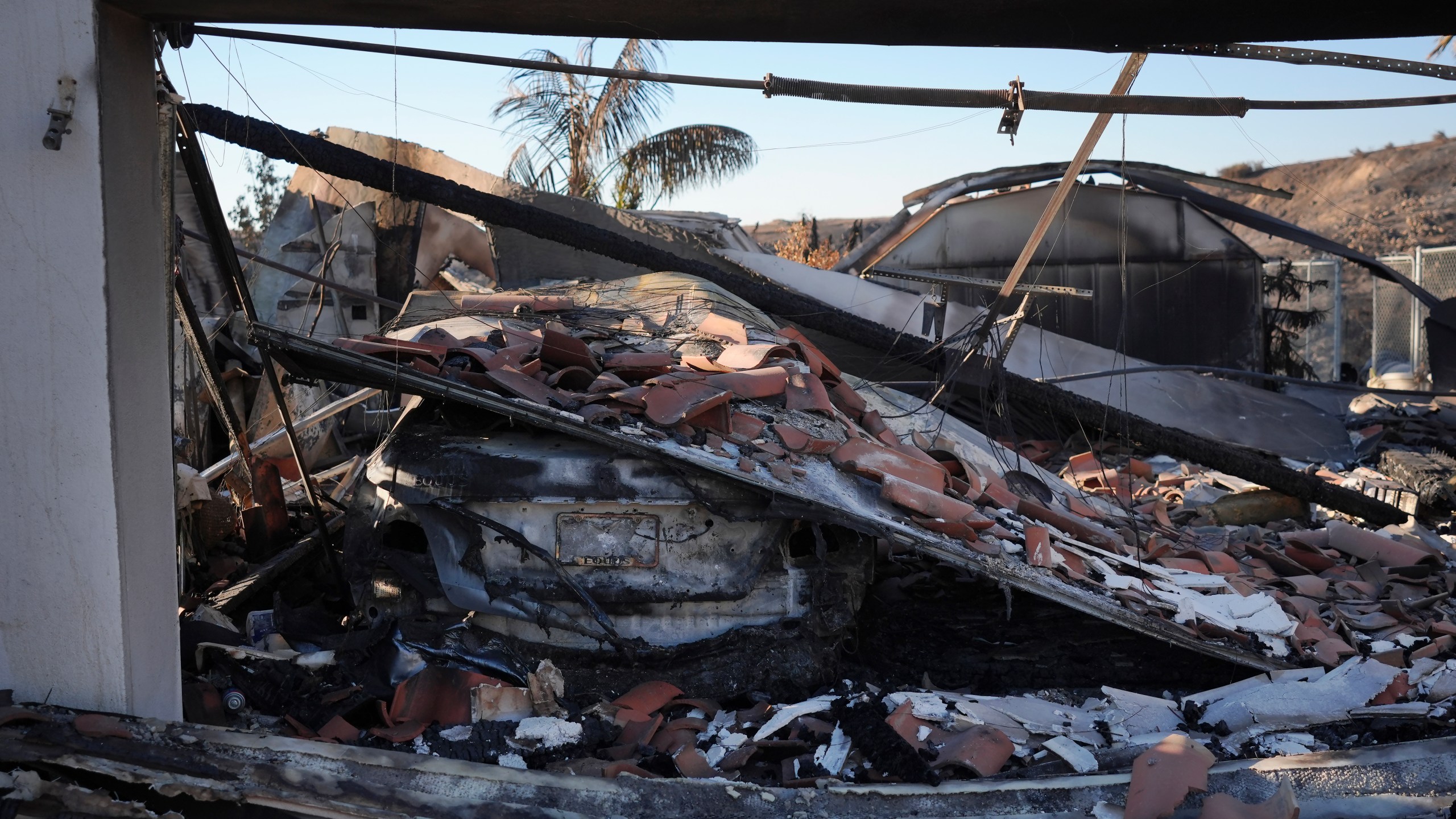 The remains of a car sit under debris at the site of a home destroyed by the Mountain Fire in Camarillo, Calif., Friday, Nov. 8, 2024. (AP Photo/Jae C. Hong)