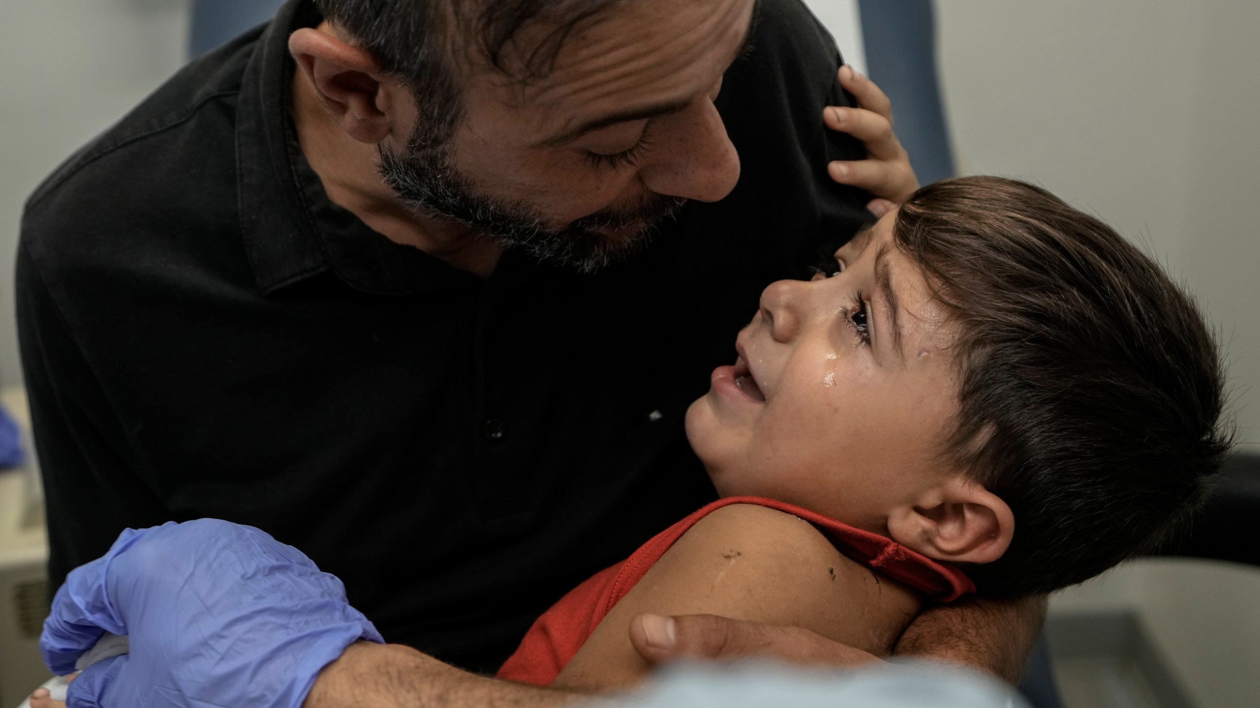 Hassan Mikdad, holds his son Hussein Mikdad, 4, who was injured on Oct. 2 in an Israeli airstrike at a densely-populated neighborhood south of Beirut, as he cries during a check up by his doctor at the American University of Beirut Medical Center (AUBMC), in Beirut, Lebanon, Tuesday, Nov. 5, 2024. (AP Photo/Bilal Hussein)