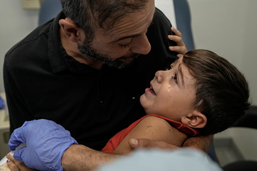 Hassan Mikdad, holds his son Hussein Mikdad, 4, who was injured on Oct. 2 in an Israeli airstrike at a densely-populated neighborhood south of Beirut, as he cries during a check up by his doctor at the American University of Beirut Medical Center (AUBMC), in Beirut, Lebanon, Tuesday, Nov. 5, 2024. (AP Photo/Bilal Hussein)