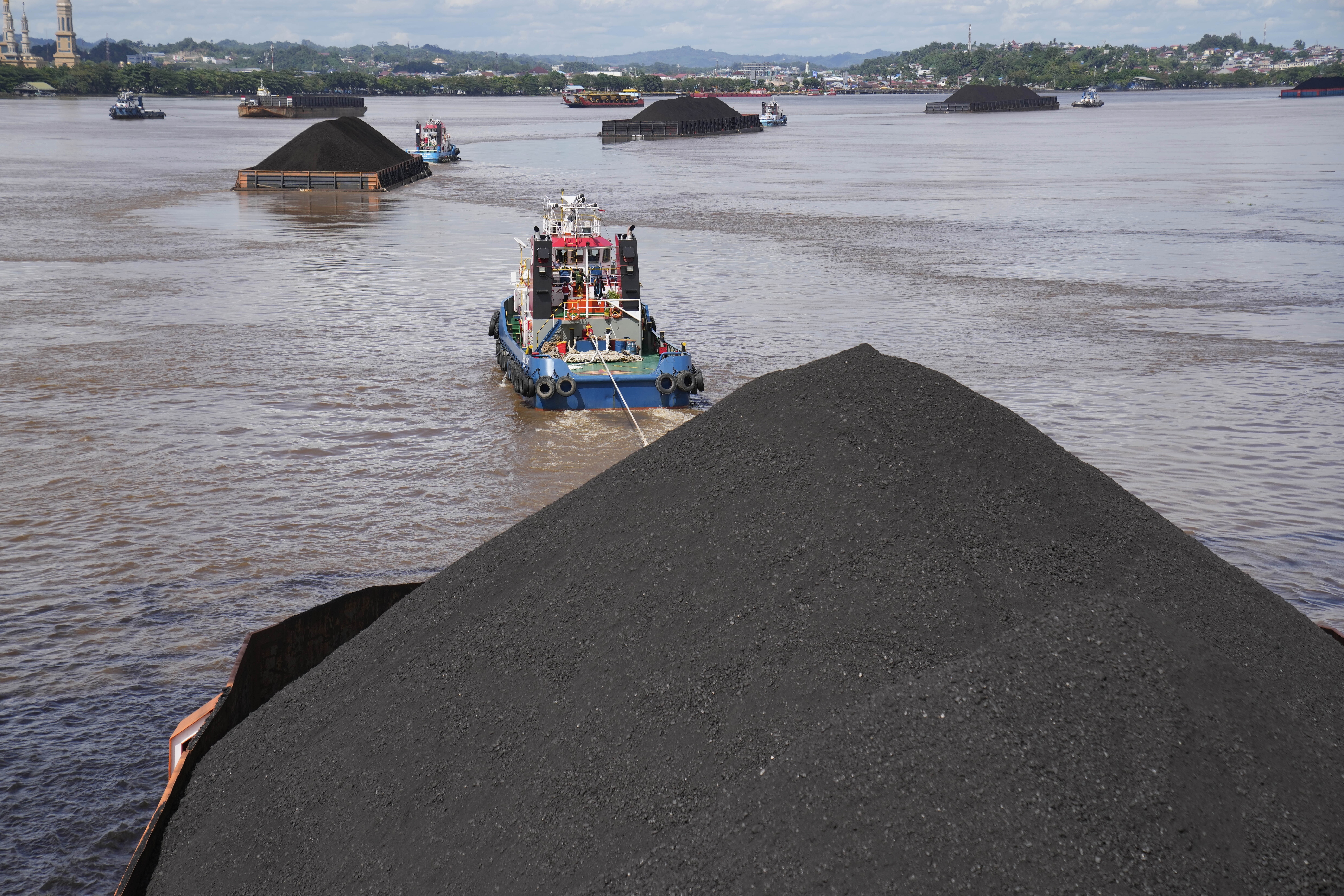 FILE - Tug boats pull barges fully loaded with coal on the Mahakam River in Samarinda, East Kalimantan, Indonesia, on Dec. 19, 2022. (AP Photo/Dita Alangkara, File)