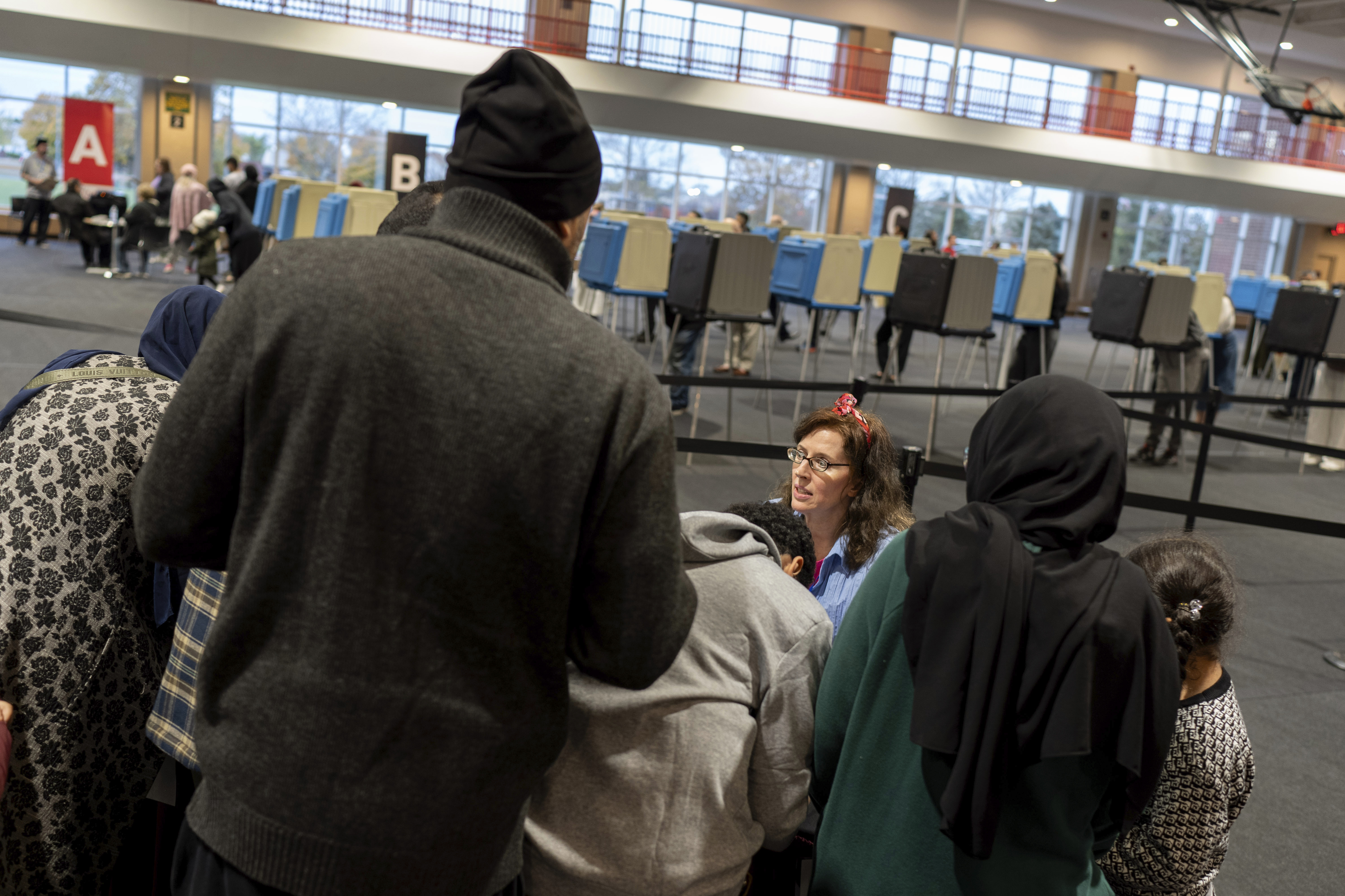 An election official helps check in voters at Ford Community and Performing Arts Center on the last day of early in-person voting, Sunday, Nov. 3, 2024, in Dearborn, Mich., the nation's largest Arab-majority city. (AP Photo/David Goldman)