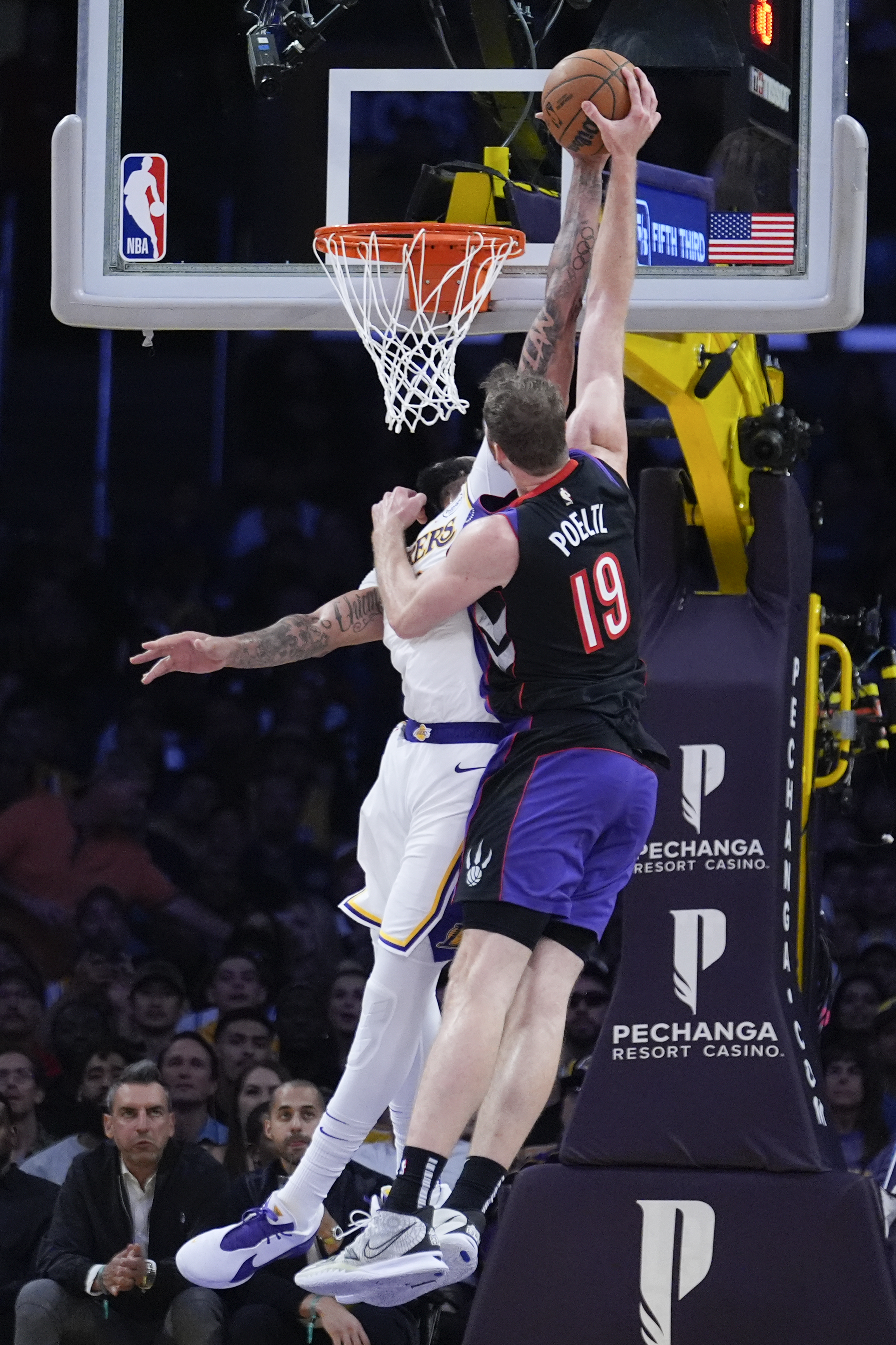 Los Angeles Lakers forward Anthony Davis, left, blocks a shot from Toronto Raptors center Jakob Poeltl (19) during the second half of an NBA basketball game Sunday, Nov. 10, 2024, in Los Angeles. (AP Photo/Marcio Jose Sanchez)