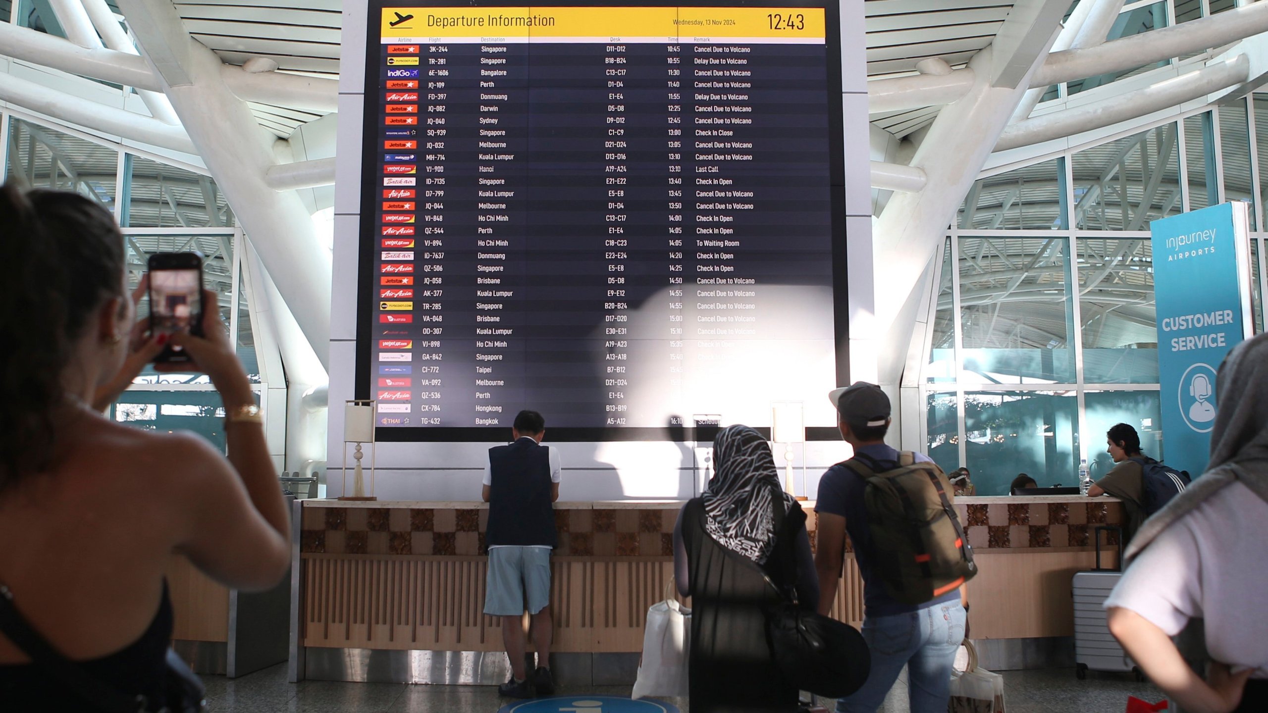 Passengers look at a flight information board showing a number of flights cancelled due to the eruption of Mount Lewotobi Laki-Laki, at Ngurah Rai International Airport in Bali, Indonesia, Wednesday, Nov. 13, 2024. (AP Photo/Firdia Lisnawati)