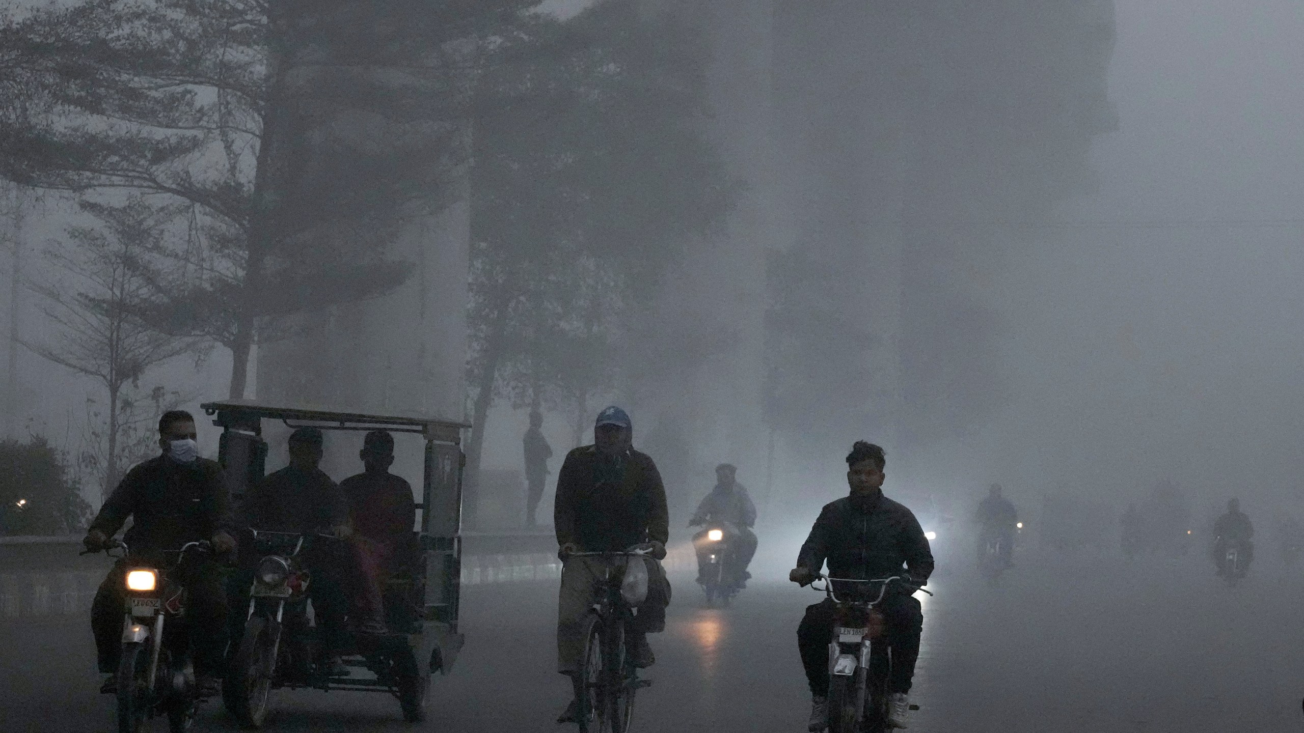 Motorcyclists move slow due to reduce visibility caused by smog enveloping the area of Lahore, Pakistan, Thursday, Nov. 14, 2024. (AP Photo/K.M. Chaudary)