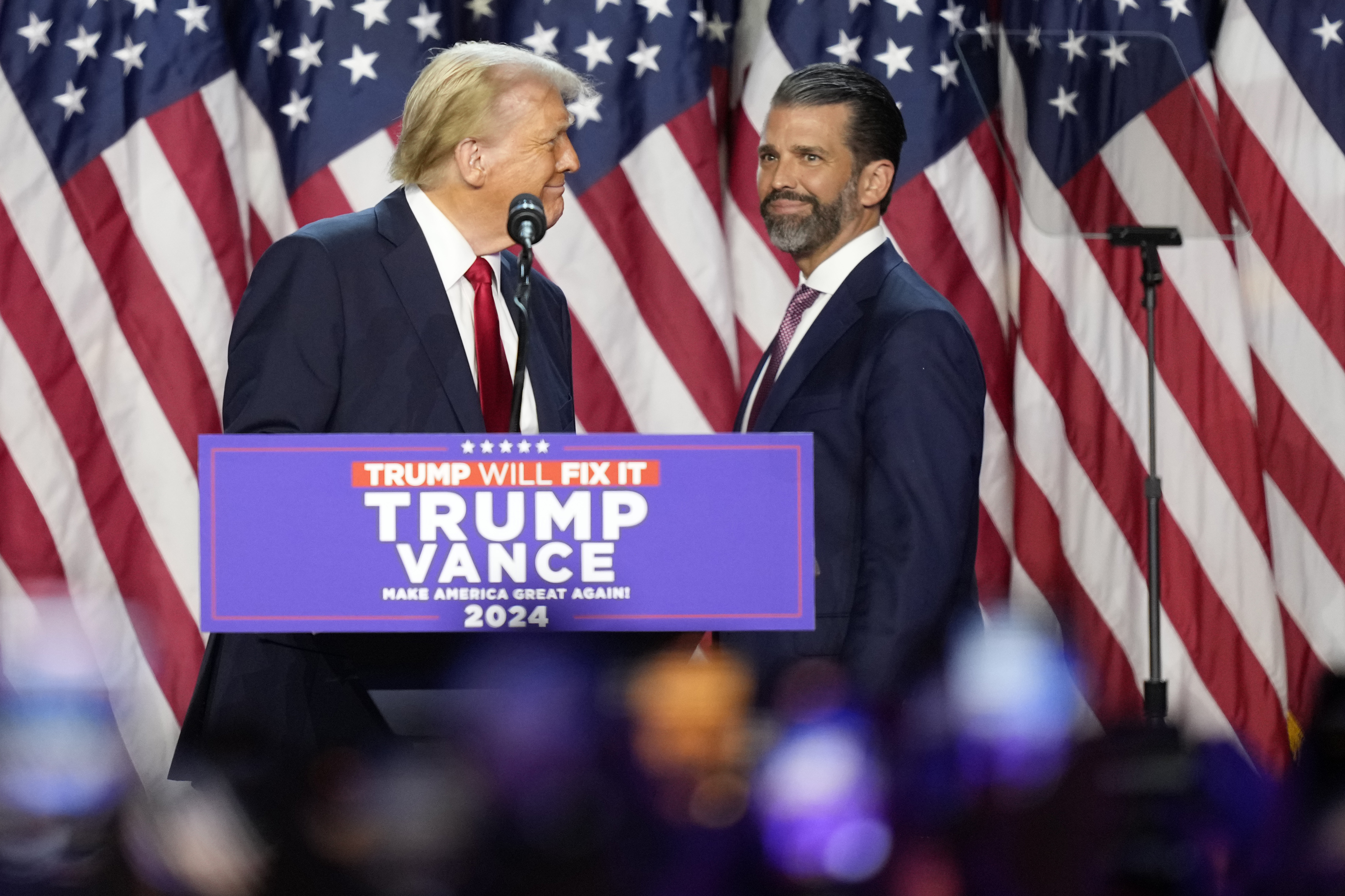 Republican presidential nominee former President Donald Trump, left, looks at his son Donald Trump Jr. at an election night watch party, Wednesday, Nov. 6, 2024, in West Palm Beach, Fla. (AP Photo/Alex Brandon)