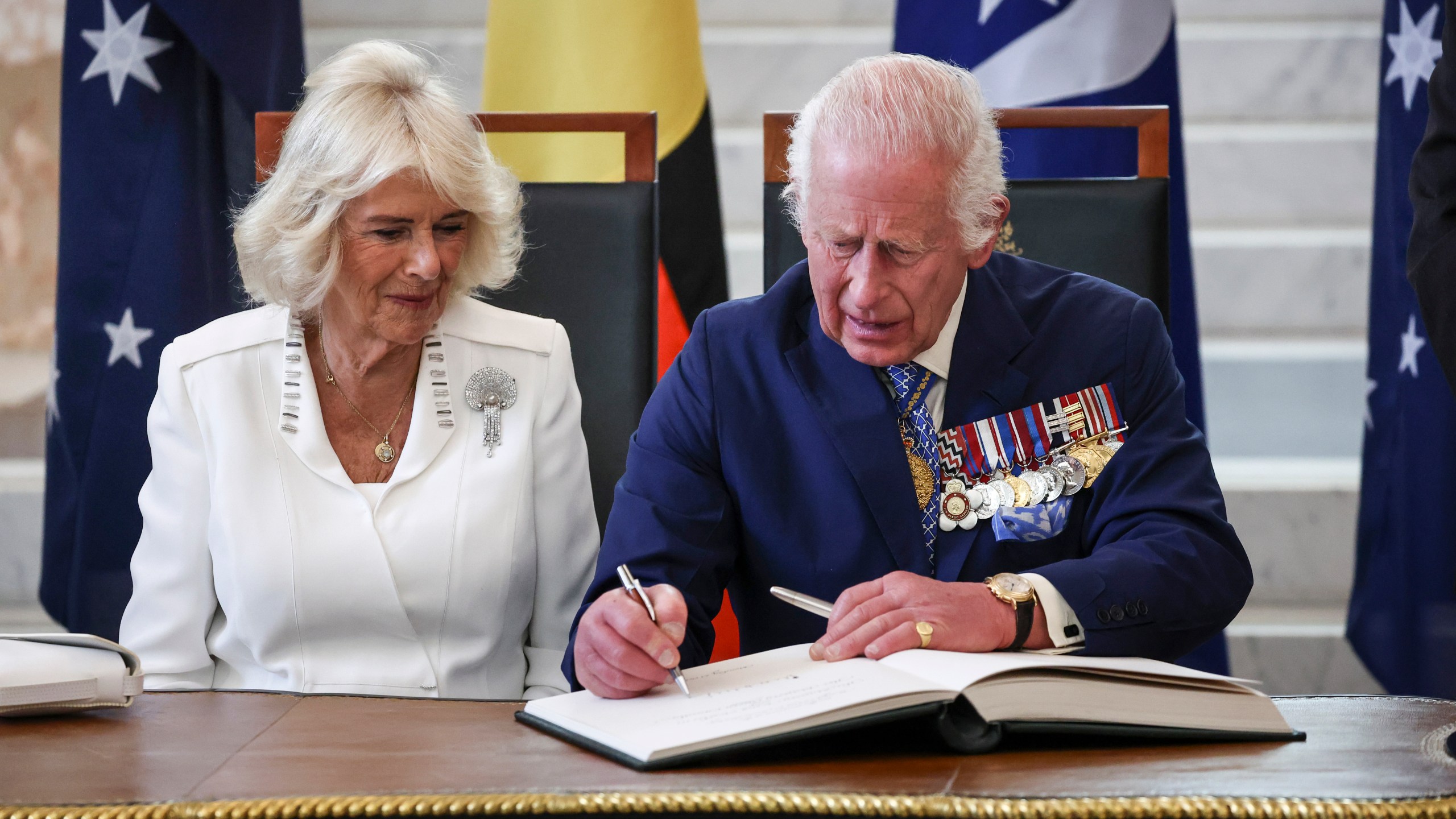 Britain's King Charles III and Queen Camilla sign a visitors' book in the Marble Foyer of Parliament House in Canberra, Australia, Monday, Oct. 21, 2024. (David Gray/Pool Photo via AP)