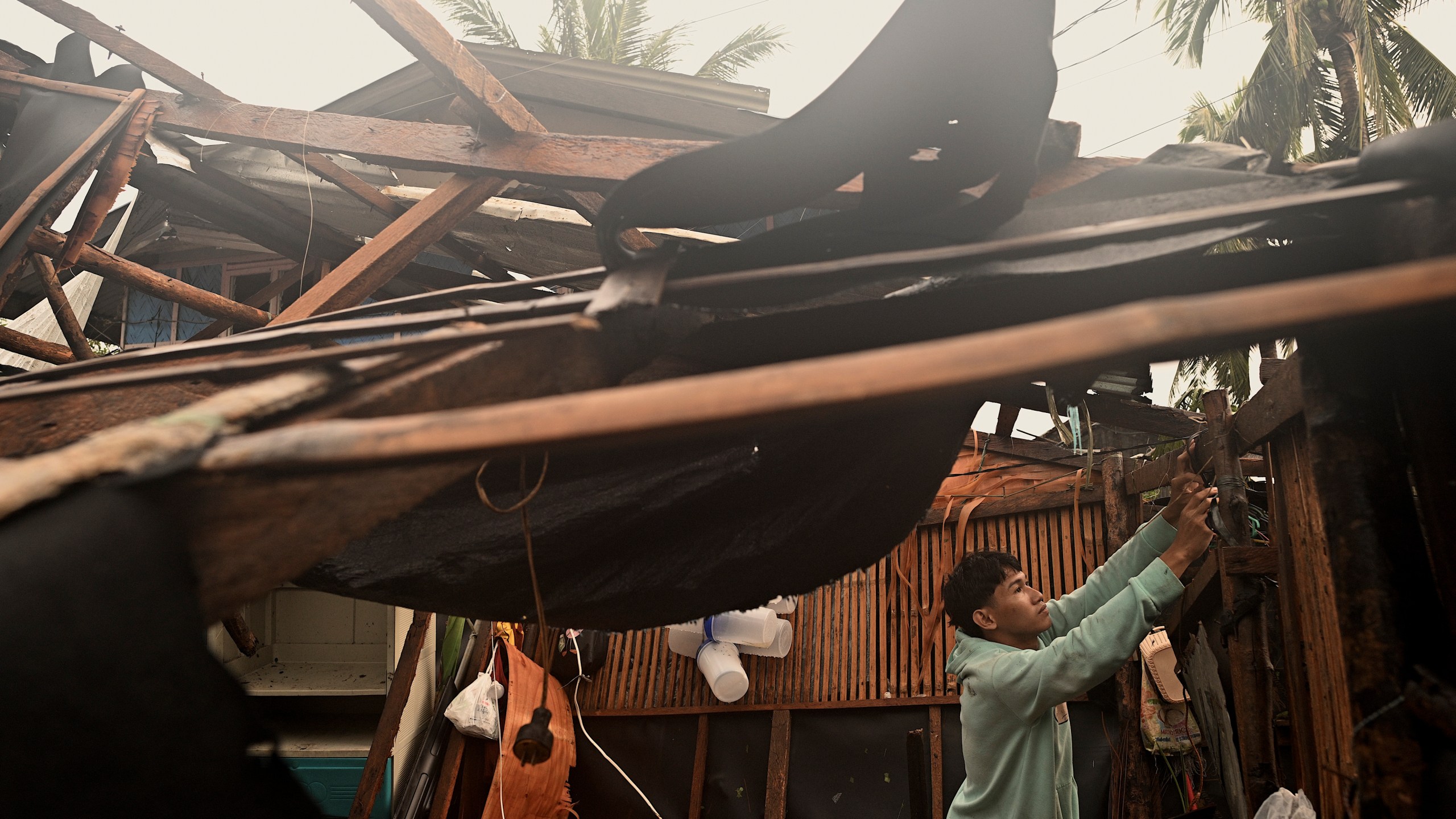 A resident checks belongings from his damaged home that was blown off by strong winds caused by Typhoon Man-yi in the municipality of Baler, Aurora province, northeastern Philippines Monday, Nov. 18, 2024. (AP Photo/Noel Celis)