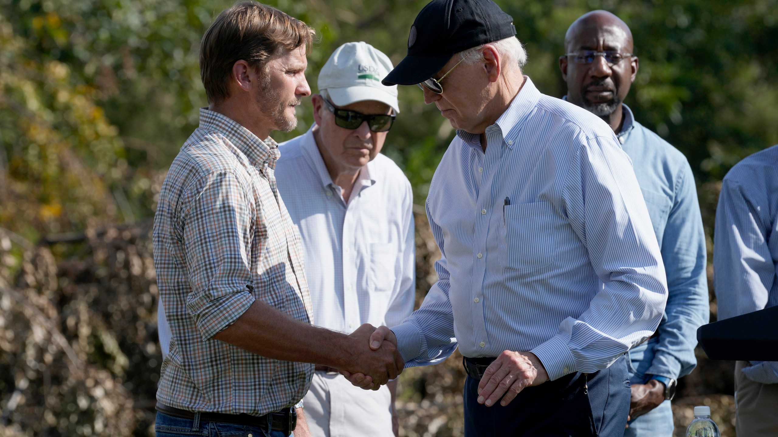 FILE - President Joe Biden, right, shakes hands with Buck Paulk, property manager of Shiloh Pecan Farm, after he spoke at the farm in Ray City, Ga., Oct. 3, 2024, as part of his trip to see areas impacted by Hurricane Helene. Looking on at right is Sen. Raphael Warnock, D-Ga. (AP Photo/Susan Walsh, File)