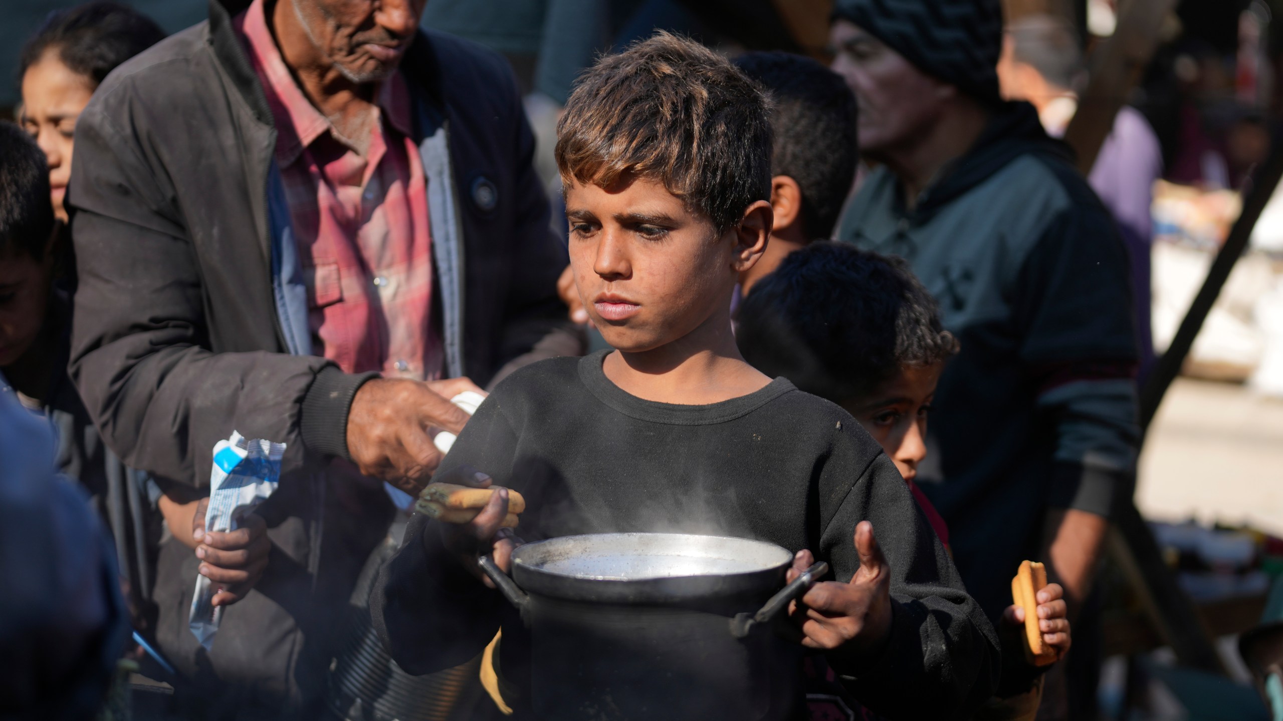 A Palestinian child queues for food in Deir al-Balah, Gaza Strip, Monday, Nov. 18, 2024. (AP Photo/Abdel Kareem Hana)