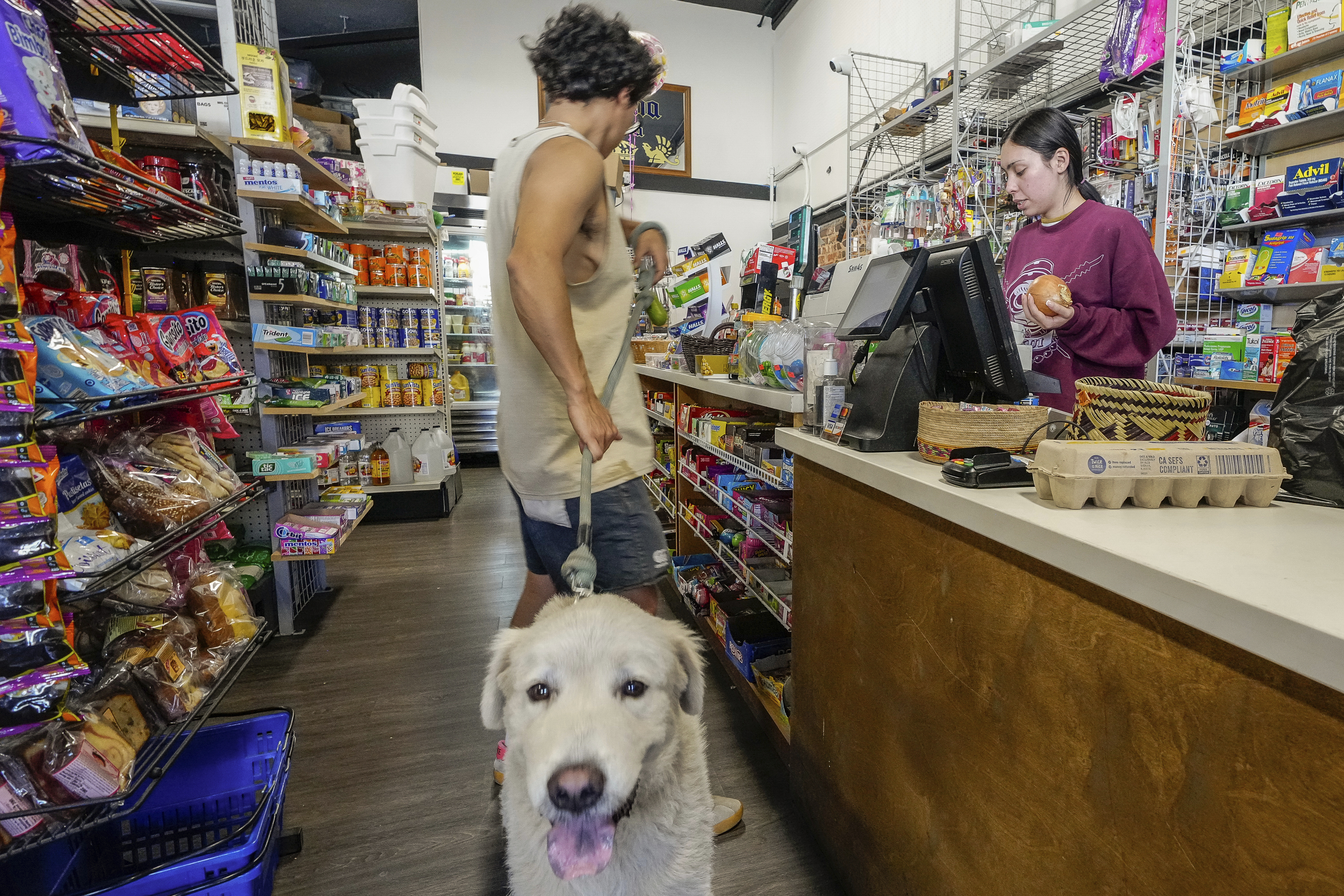 College student Jimena Sanchez, right, who studies children's development works as a part-time cashier earning minimum wage at a family store, in Los Angeles on Friday, Oct. 11, 2024. (AP Photo/Damian Dovarganes)