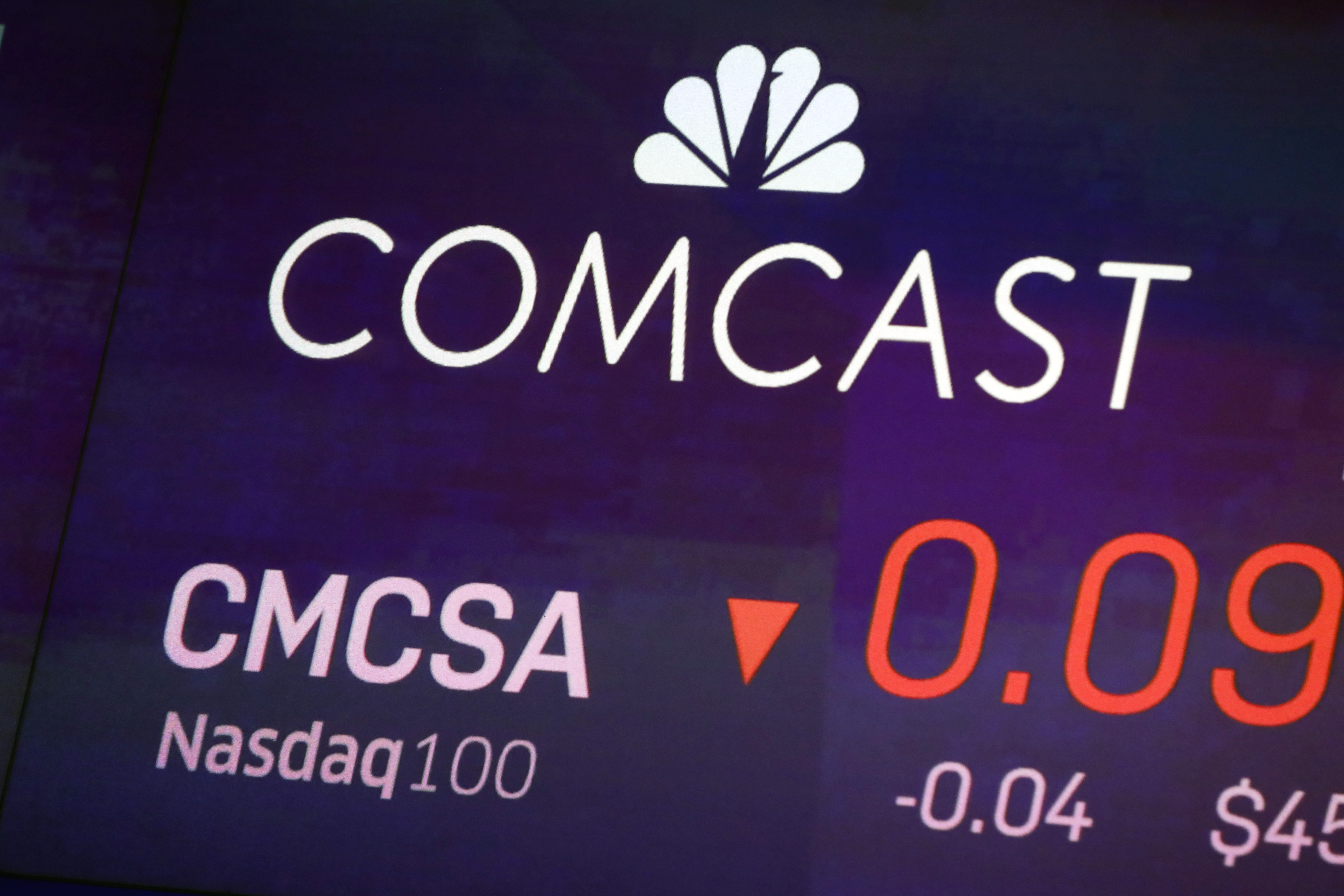 FILE - The symbol for Comcast appears on a screen at the Nasdaq MarketSite, on Oct. 1, 2019 in New York. (AP Photo/Richard Drew, File)