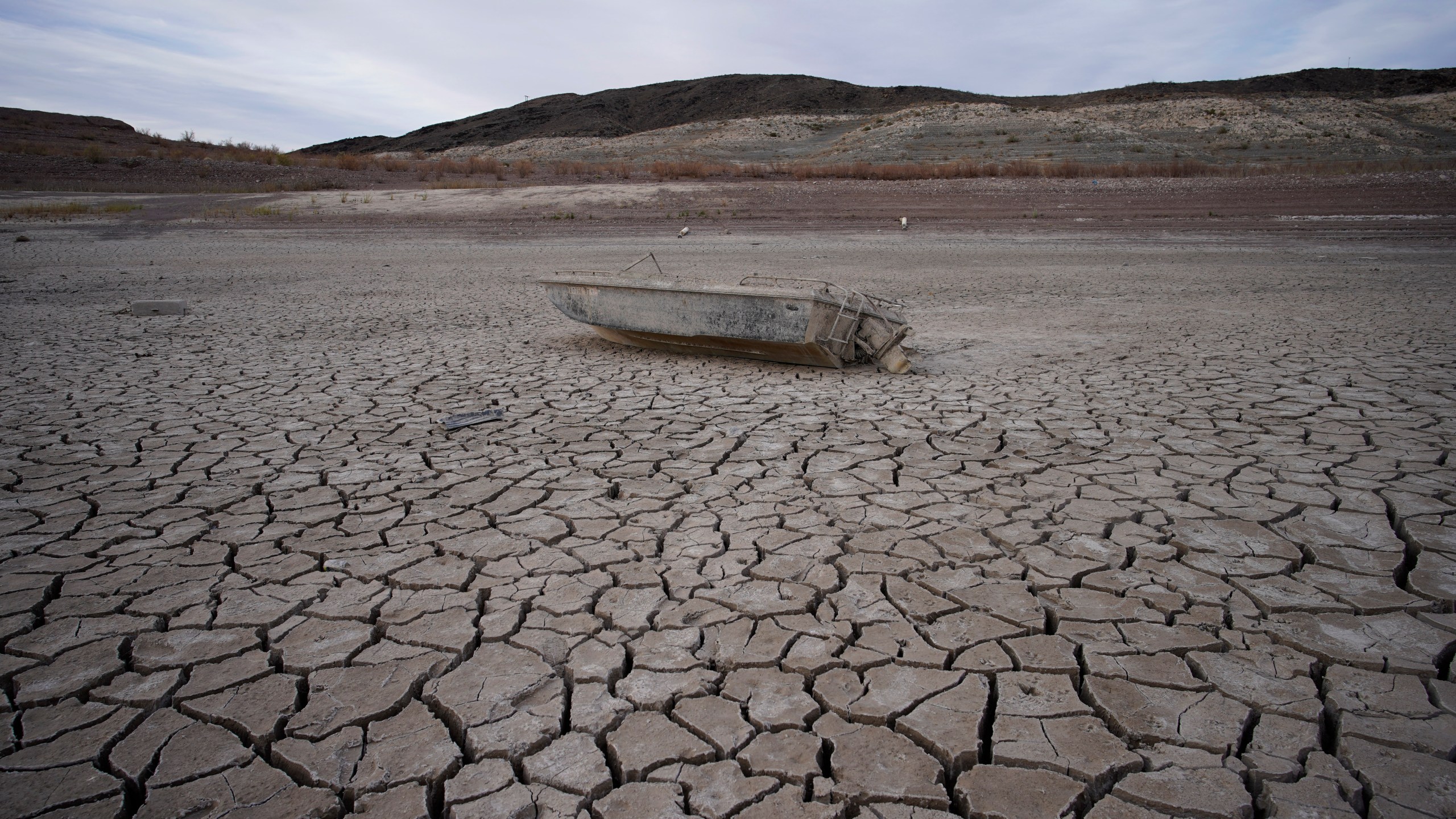 FILE - A formerly sunken boat sits on cracked earth hundreds of feet from the shoreline of Lake Mead at the Lake Mead National Recreation Area on May 10, 2022, near Boulder City, Nev. (AP Photo/John Locher, File)