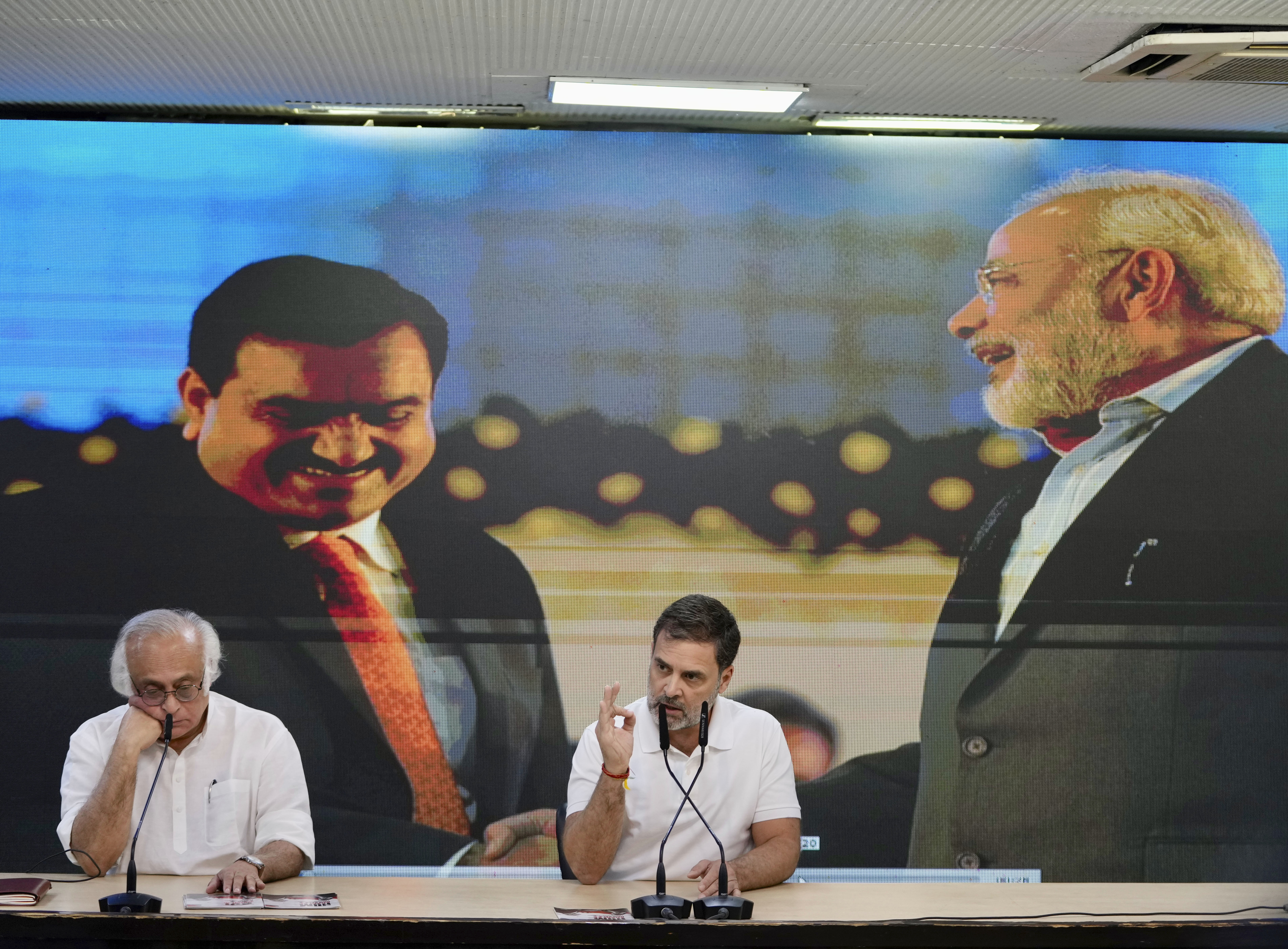 India's opposition Congress party leader Rahul Gandhi, center, addresses the media on Indian businessman Gautam Adani, after Adani was indicted by U.S. prosecutors on charges he duped investors in a massive solar energy project in India, in New Delhi, India, Thursday, Nov. 21, 2024. Image behind shows Adani, on left with Indian Prime Minister Narendra Modi, on right. (AP Photo/Manish Swarup)