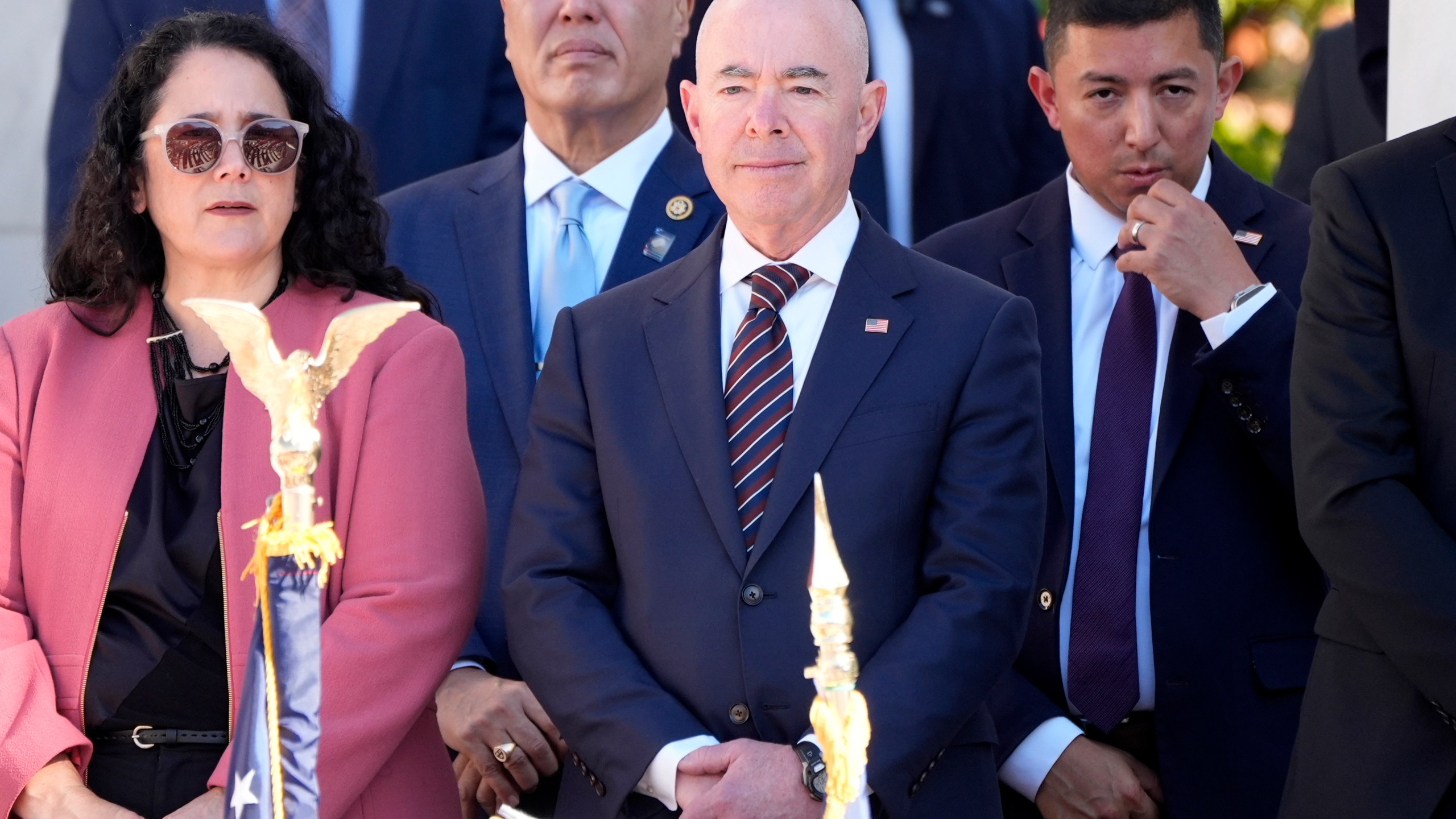 Homeland Security Secretary Alejandro Mayorkas, center, looks on before President Joe Biden speaks at the National Veterans Day Observance at the Memorial Amphitheater at Arlington National Cemetery in Arlington, Va., Monday, Nov. 11, 2024. (AP Photo/Mark Schiefelbein)