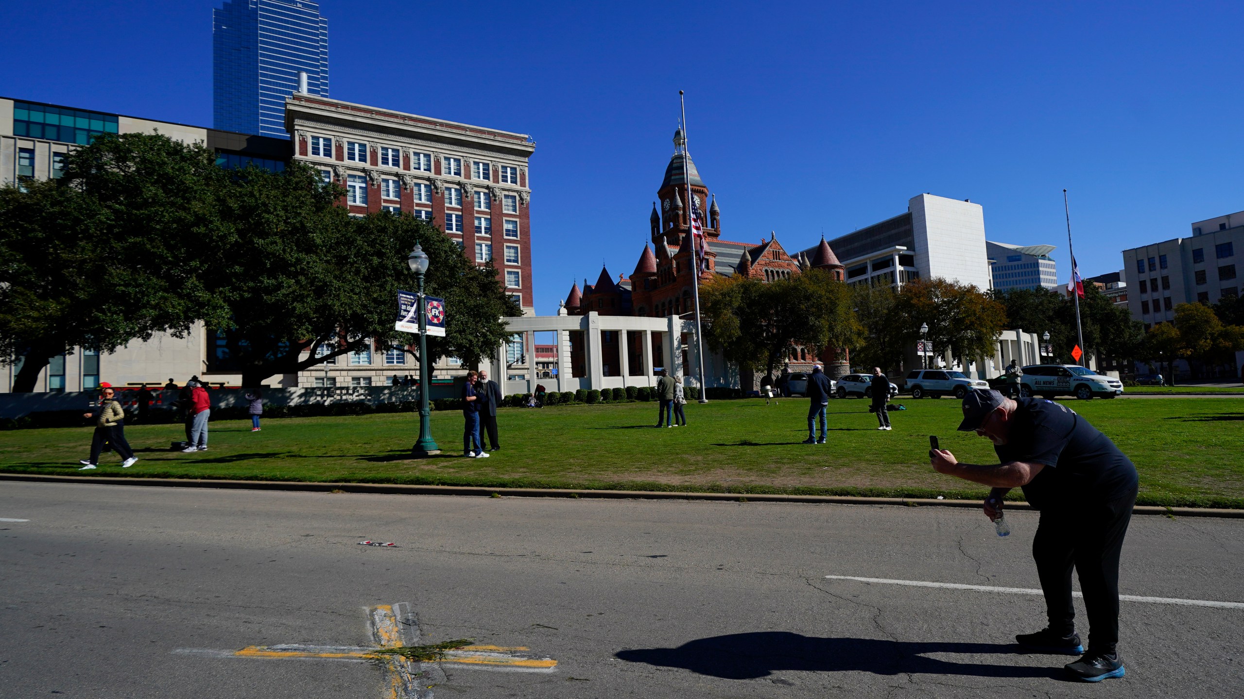 FILE - A person uses a cell phone to capture images of an X on Elm Street at Dealey Plaza, one of two spots marked where President John F. Kennedy was shot, as people gather on the 60th anniversary of his assassination, Nov. 22, 2023, in Dallas. (AP Photo/Julio Cortez, File)