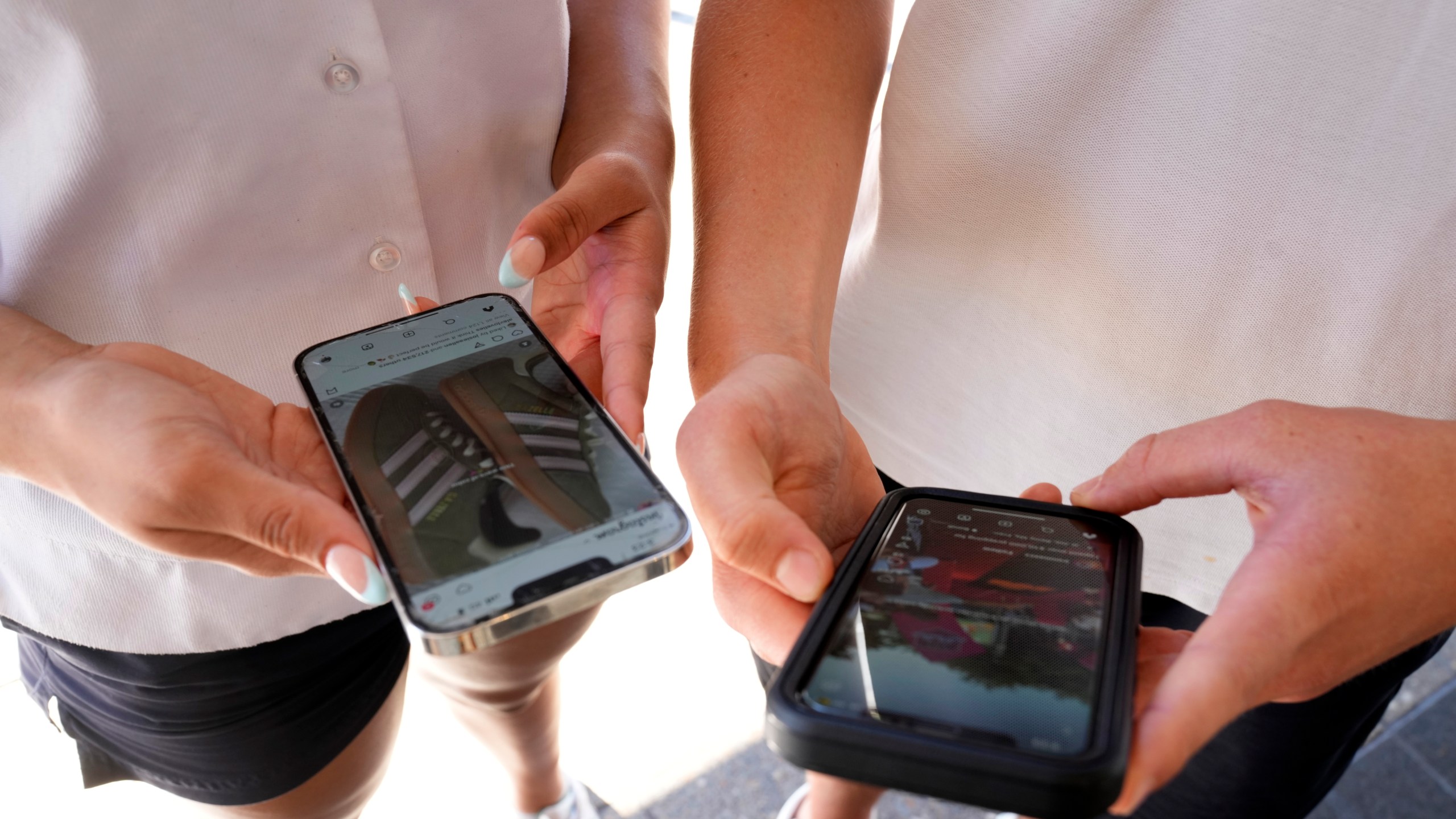 14-year-old Henry, right, and Angel, 15, use their phones to view social media in Sydney, Friday, Nov. 8, 2024. (AP Photo/Rick Rycroft)