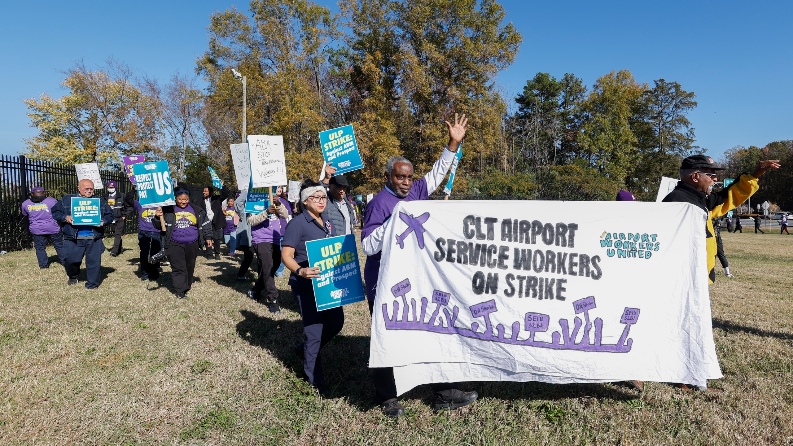 Airport workers wave signs as they march in front of the Charlotte Douglas International Airport in Charlotte, N.C., Monday, Nov. 25, 2024. (AP Photo/Nell Redmond)