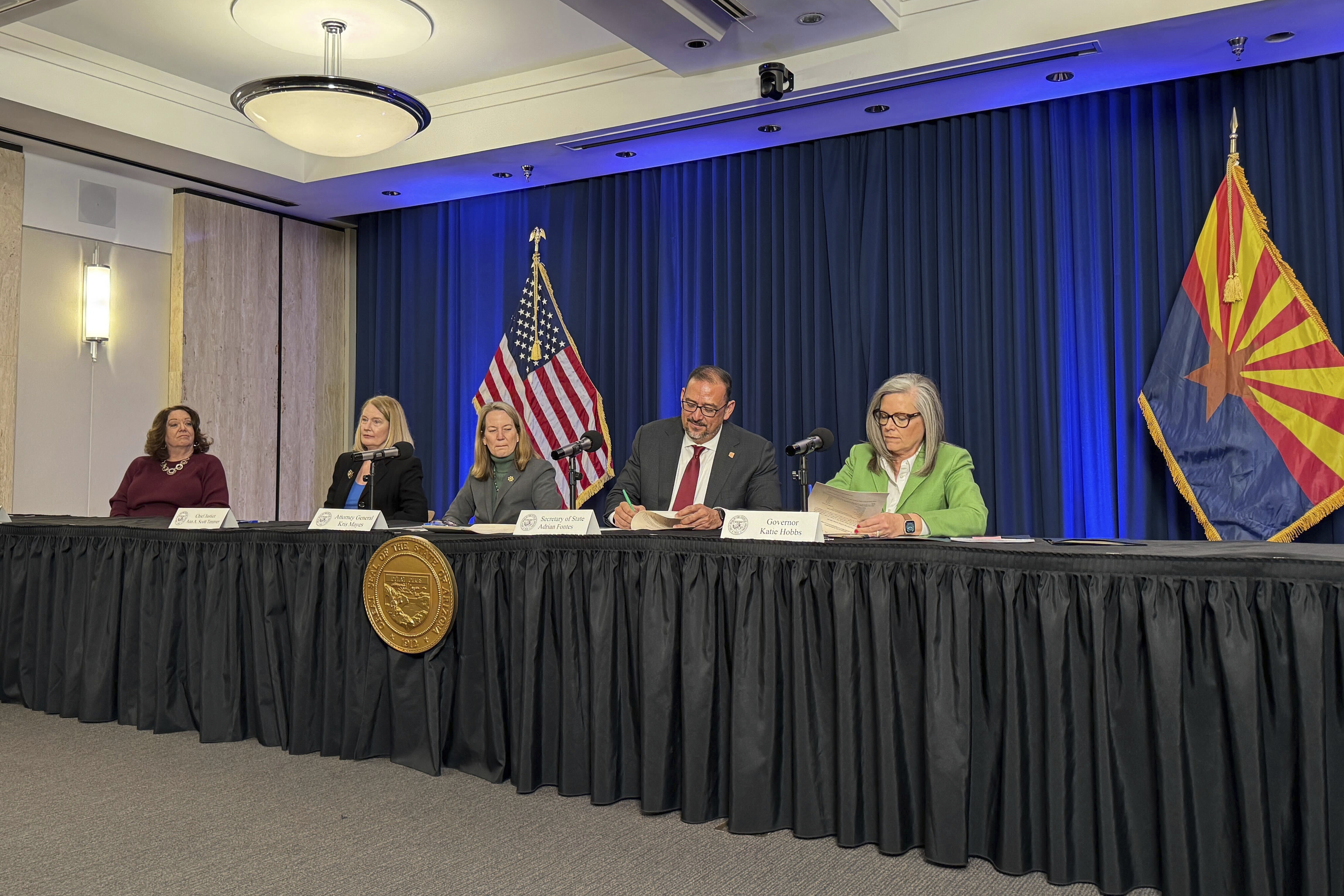 Arizona Gov. Katie Hobbs, right, and Secretary of State Adrian Fontes sign off on election results as state Attorney General Kris Mayes, Arizona Supreme Court Chief Justice Ann Timmer and state election director Lisa Marra look on during the state canvassing meeting in Phoenix, Monday, Nov. 25, 2024. (AP Photo/Gabriel Sandoval)