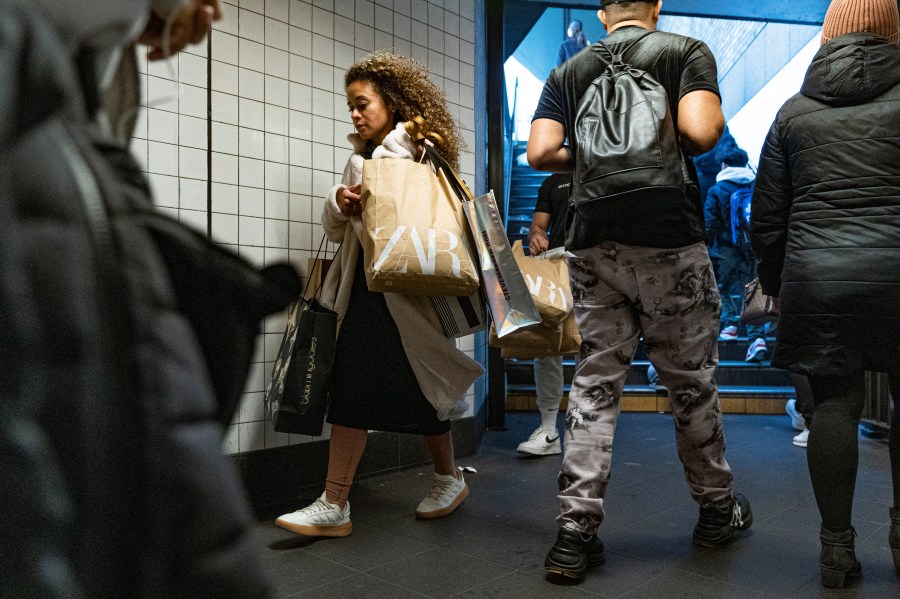 FILE - A woman carrying shopping bags enters the Broadway-Lafayette Street subway station on Black Friday in New York, Nov. 24, 2023. (AP Photo/Peter K. Afriyie, File)