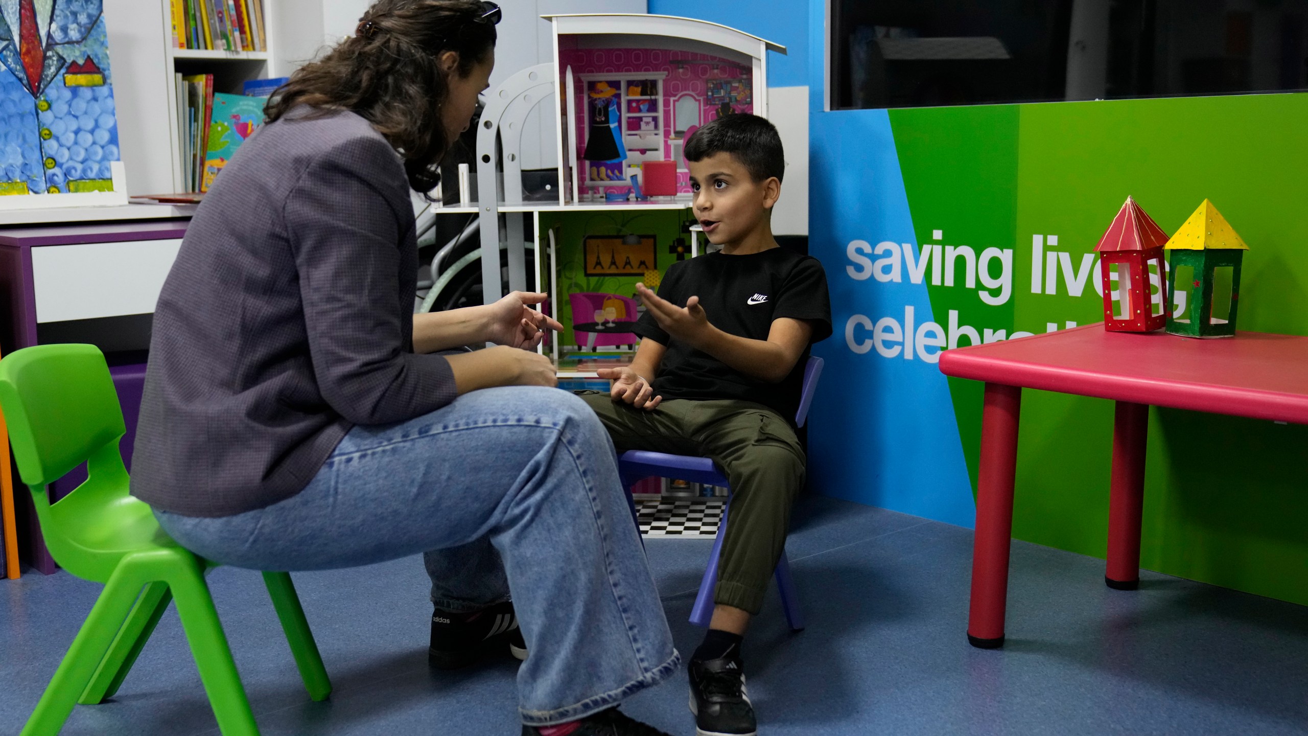 Mohammad Mousawi, 8, a displaced boy from the southern suburb of Beirut who suffers from leukaemia, attends with a volunteer who offers him a compassionate care and entertainment ahead of his weekly treatment at the Children's Cancer Center of Lebanon, in Beirut, Lebanon, Friday, Nov. 15, 2024. (AP Photo/Hussein Malla)