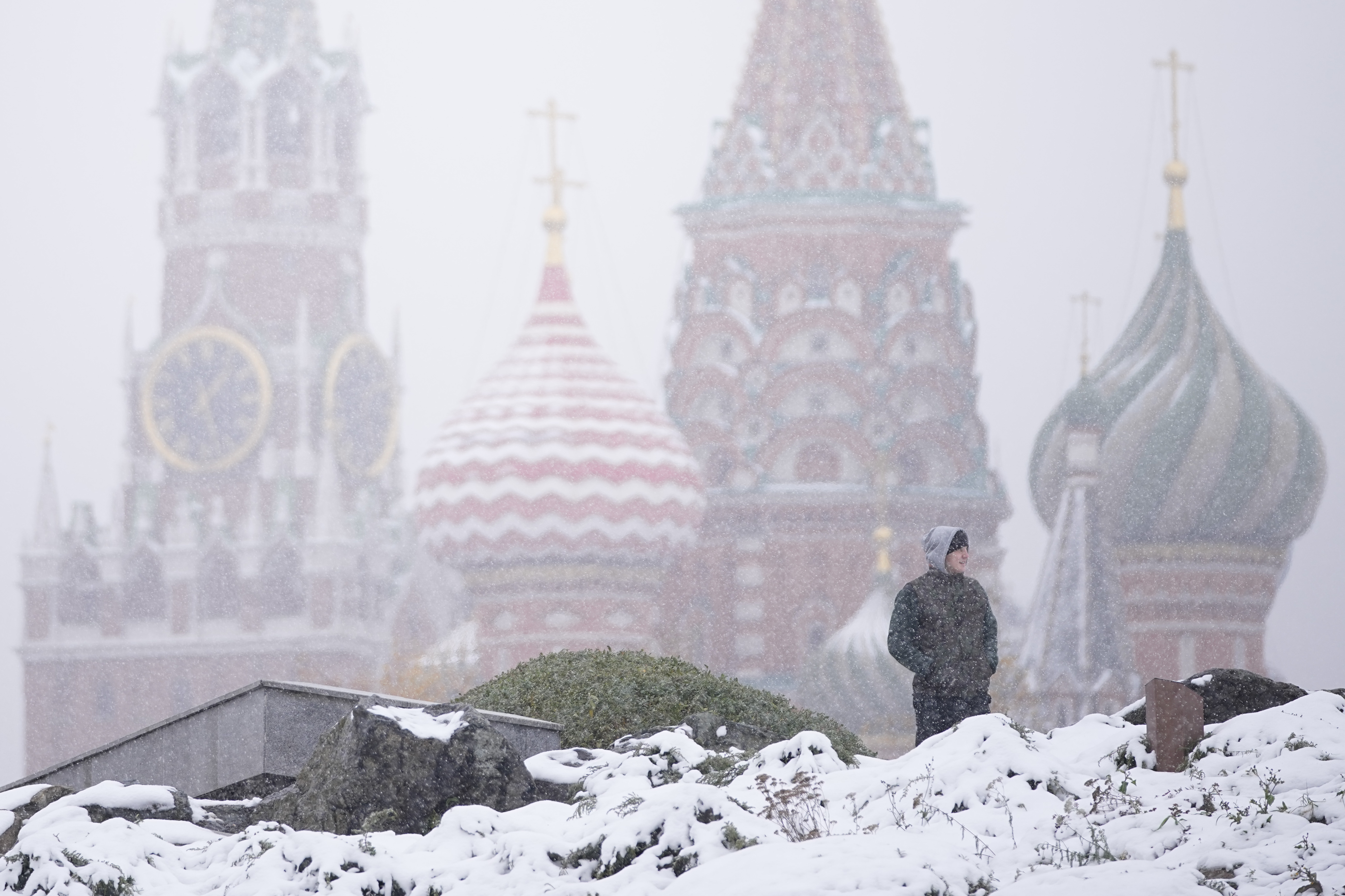 A man walks at Zaryadye park with the Spasskaya tower of the Kremlin and St. Basil's Cathedral in the background during a snowfall in Moscow, Russia, Wednesday, Nov. 6, 2024. (AP Photo/Pavel Bednyakov)