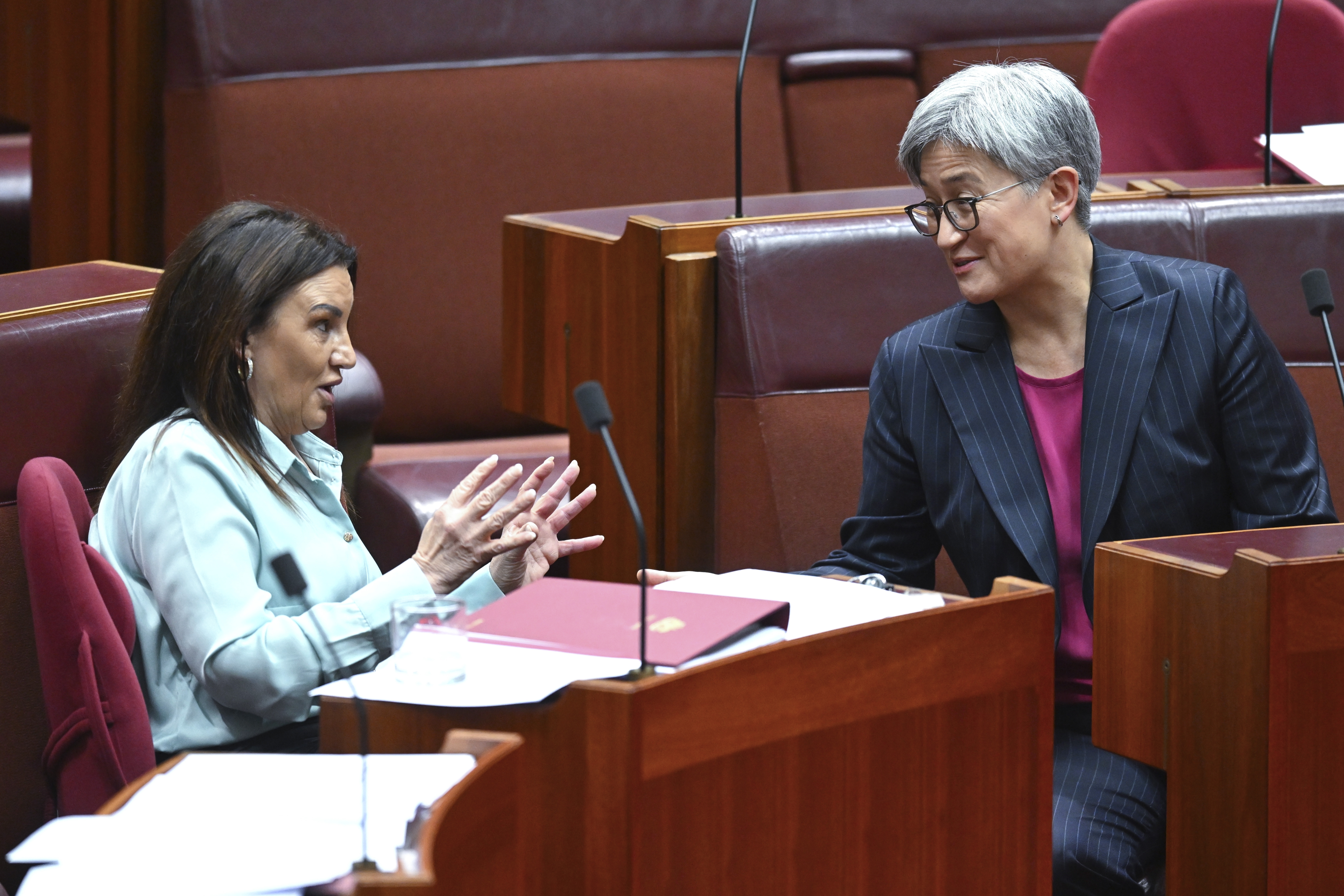 Senator Jacqui Lambie, left, gestures as she speaks to Australian Foreign Minister Penny Wong during debate in the Senate chamber at Parliament House in Canberra, Australia, Thursday, Nov. 28, 2024. (Lukas Coch/AAP Image via AP)