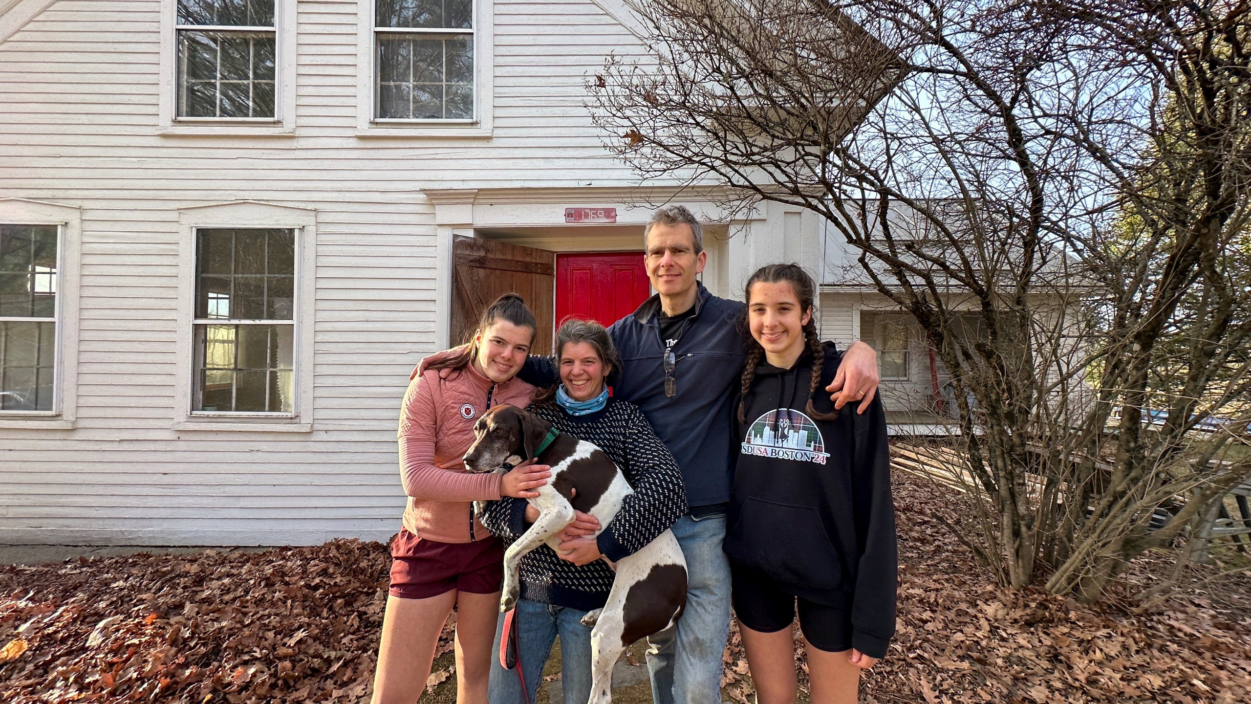 The Mackenzies, from left to right, Lila, Jenny, John, Kate and their dog Hester pose in front of their new house in Craftsbury, Vt. on Nov. 17, 2024. (AP Photo/Lisa Rathke)