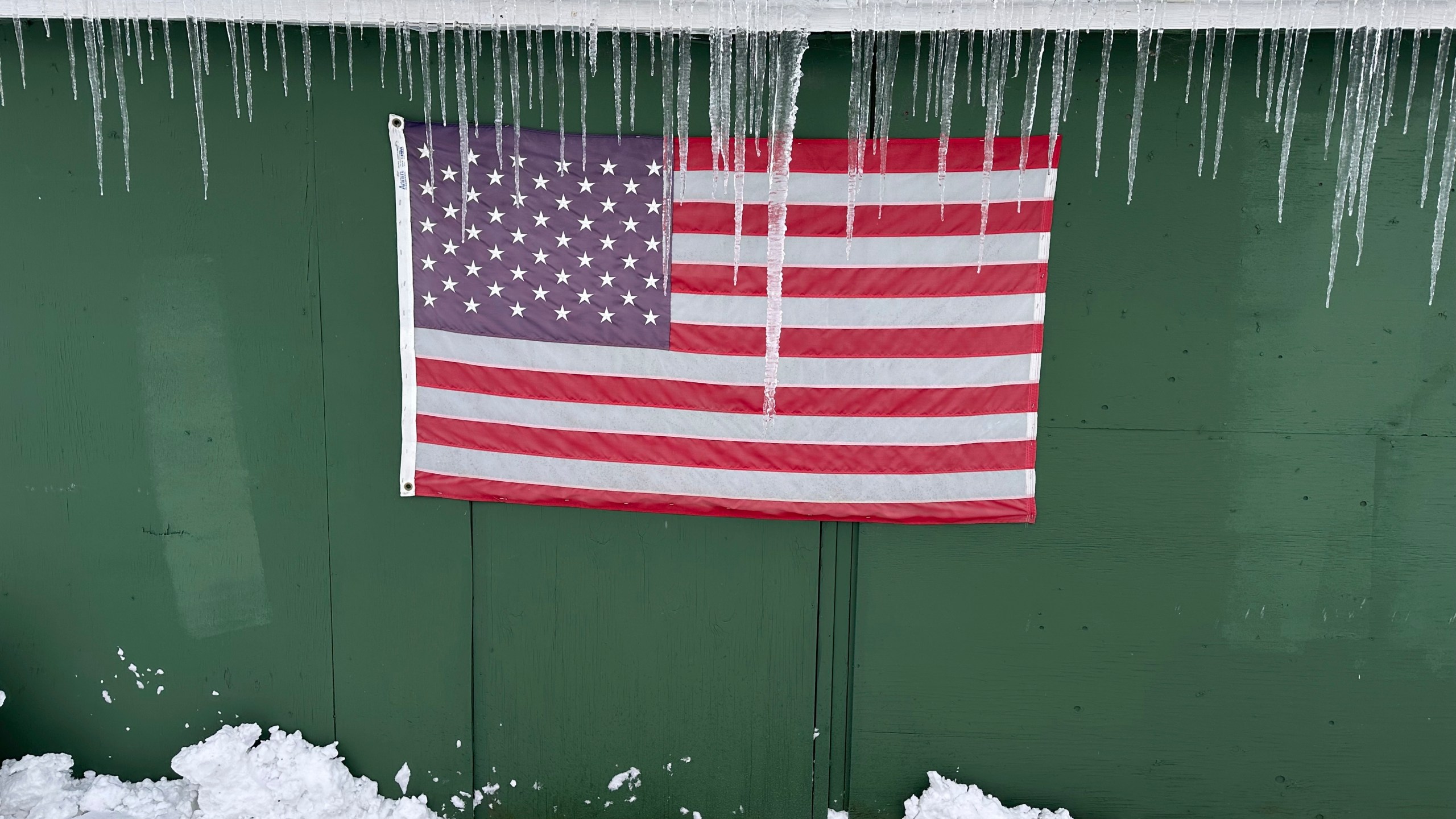 Icicles form over a flag during a snow storm, in Lowville, N.Y., on Sunday Dec, 1, 2024. (AP Photo/Cara Anna)