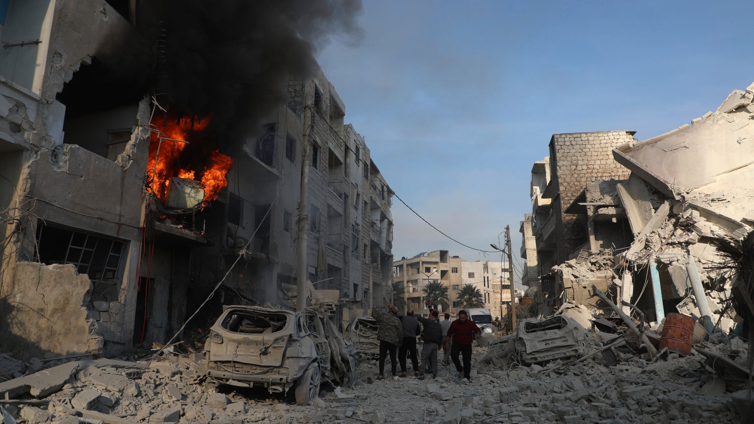 This photo provided by the Syrian Civil Defence White Helmets, which has been authenticated based on its contents and other AP reporting, shows Syrian residents gather near destroyed buildings, after Syrian government forces hit Idlib city, Syria, Monday, Dec. 2, 2024. (Syrian Civil Defence White Helmets via AP)