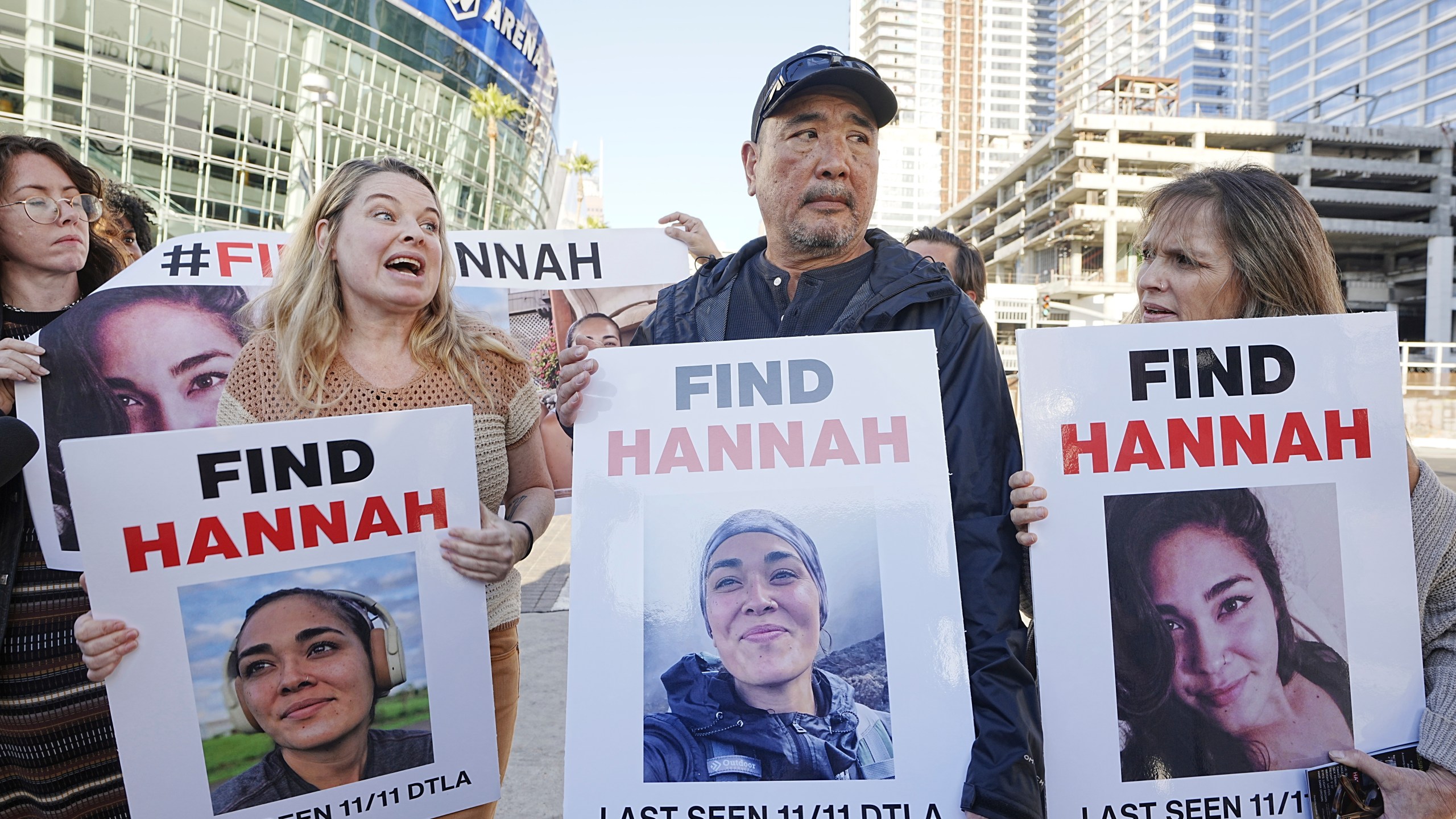 Ryan Kobayashi, center, holds a picture of his missing daughter Hannah Kobayashi outside Crypto.com Arena, Thursday, Nov. 21, 2024 in Los Angeles. (AP Photo/Damian Dovarganes)