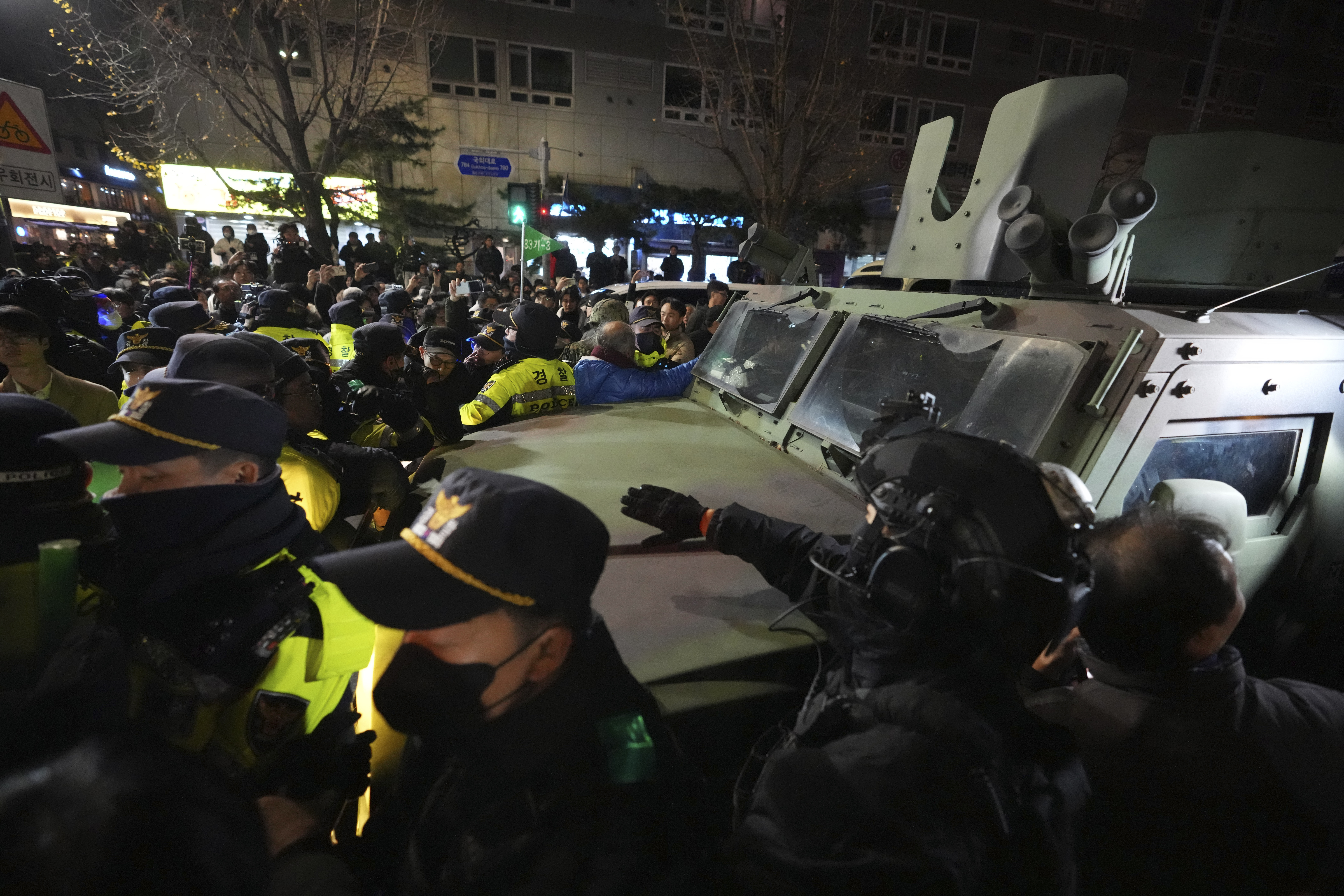 Military vehicle is escorted by police officers as people try to block outside of the National Assembly in Seoul, South Korea, Wednesday, Dec. 4, 2024. (AP Photo/Lee Jin-man)