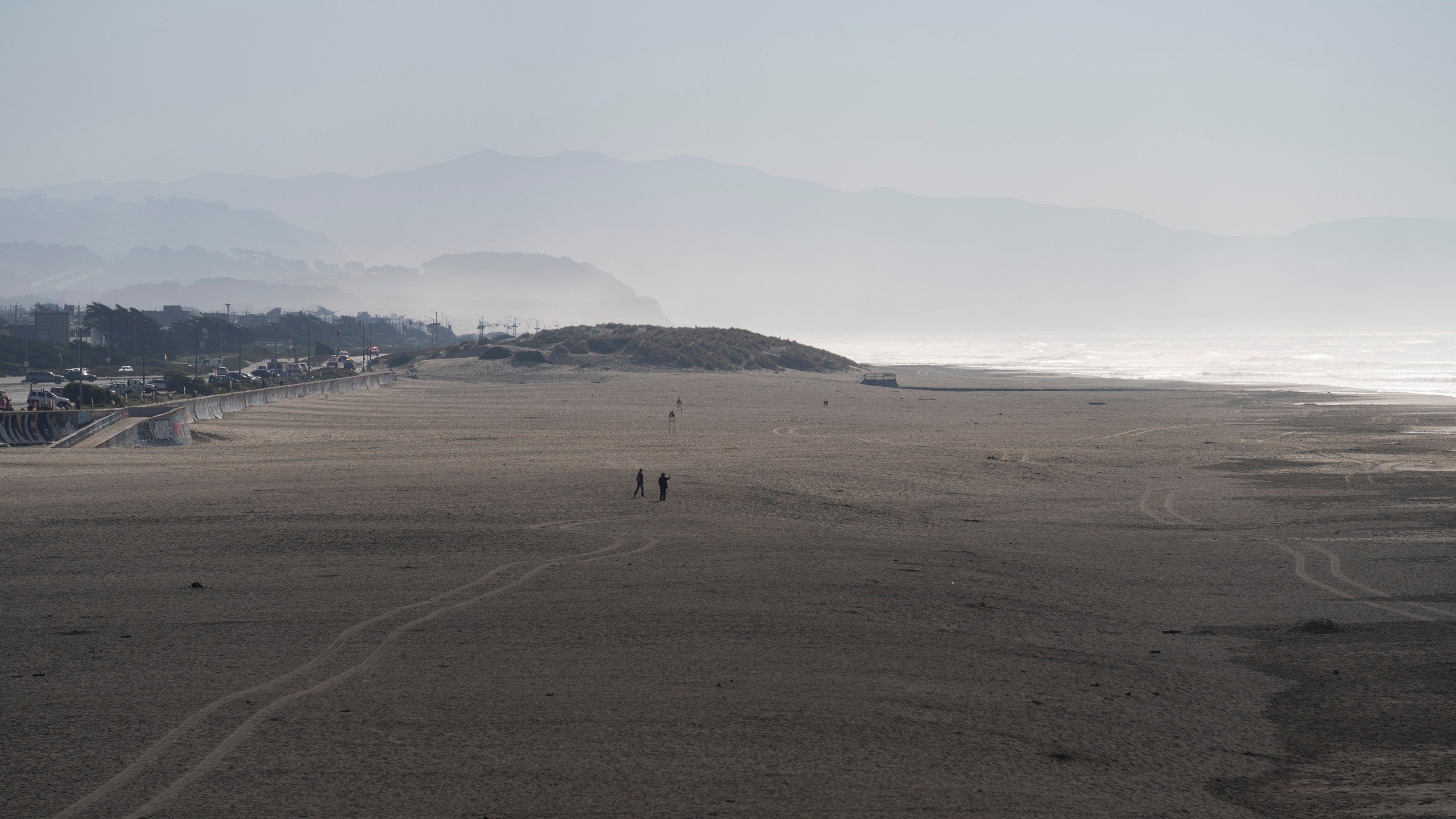 People walk onto the sand at Ocean Beach in San Francisco during a tsunami warning on Thursday, Dec. 5, 2024. (AP Photo/Emily Steinberger)