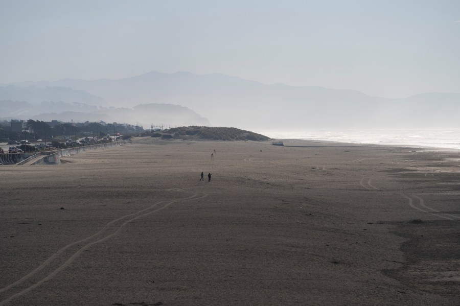 People walk onto the sand at Ocean Beach in San Francisco during a tsunami warning on Thursday, Dec. 5, 2024. (AP Photo/Emily Steinberger)