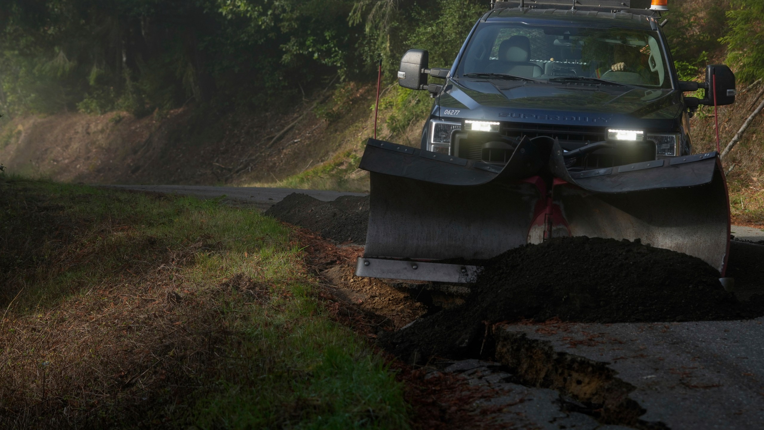 Humboldt County road maintenance supervisor Wayne Tomasini fills in cracks with dirt on a road damaged by a 7.0 earthquake in Humboldt County, Calif., Friday, Dec. 6, 2024. (AP Photo/Godofredo A. Vásquez)