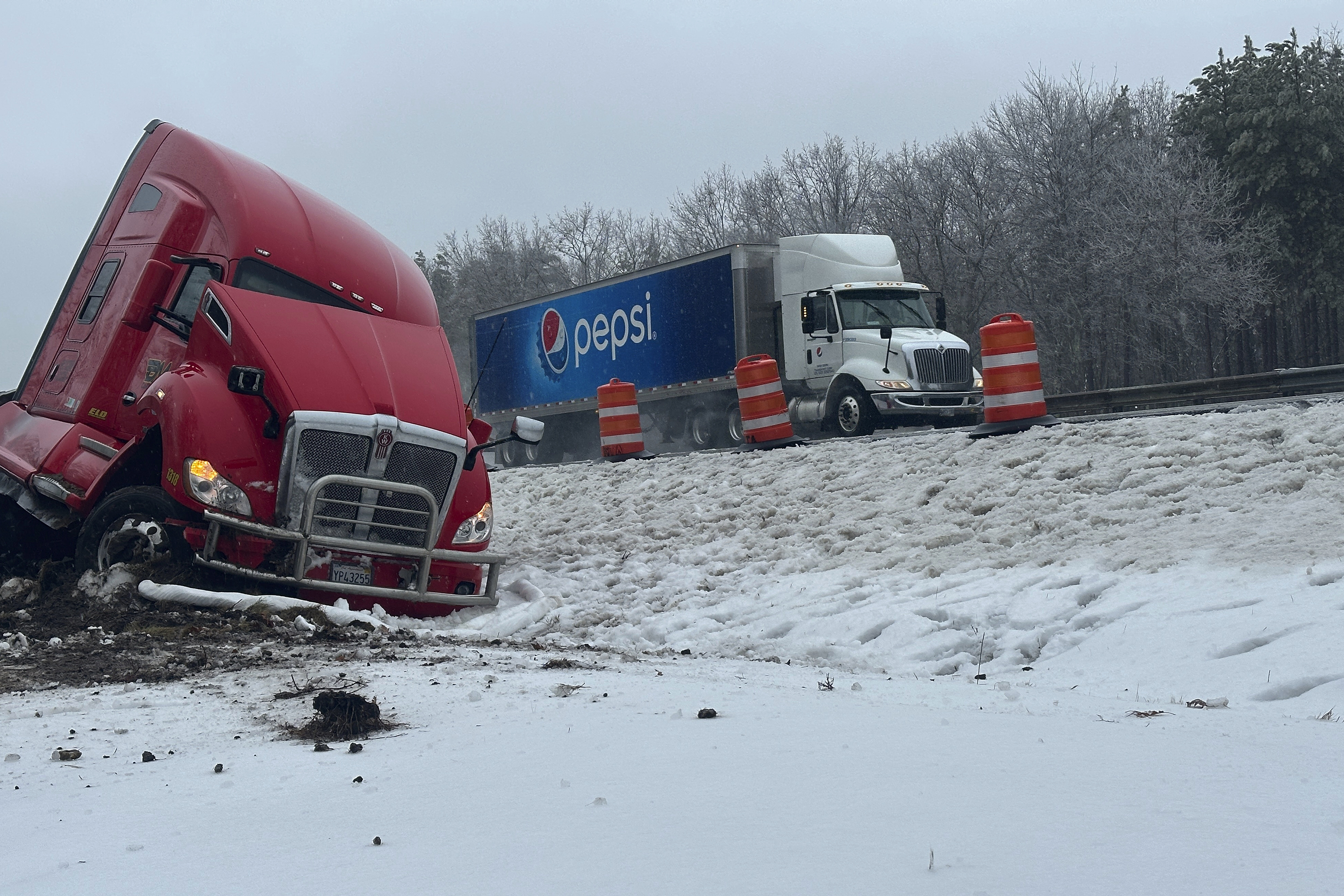 A tractor-trailer hauling a load of oranges sits on the side of the road after sliding off the Maine Turnpike early on Wednesday, Dec. 11, 2024, in New Gloucester, Maine. (AP Photo/David Sharp)