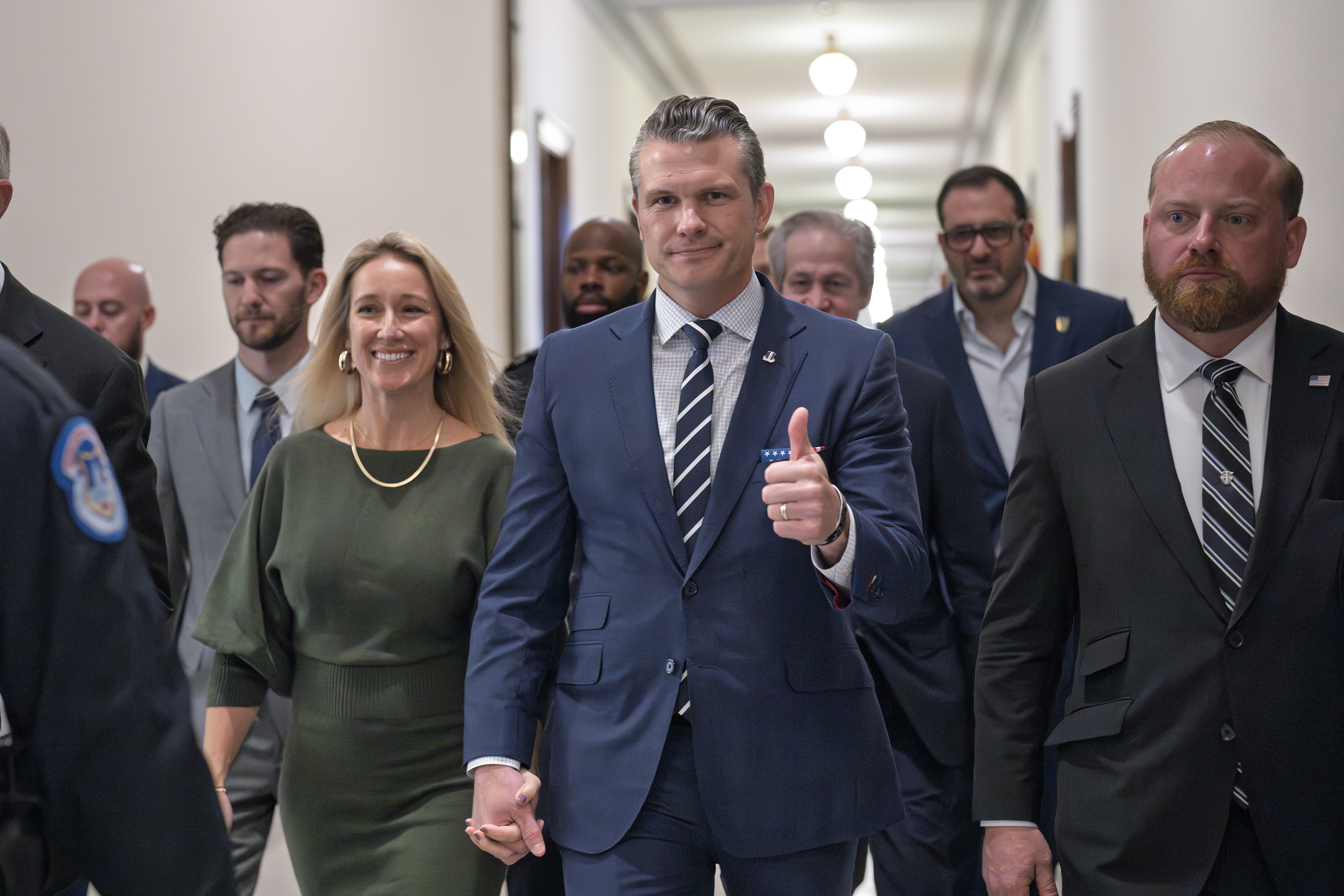 Pete Hegseth, President-elect Donald Trump's nominee to be Defense Secretary, gives a thumbs-up as he walks with his wife Jennifer Rauchet, left, to meet with Sen. Joni Ernst, R-Iowa, a member of the Senate Armed Services Committee, at the Capitol in Washington, Monday, Dec. 9, 2024. (AP Photo/J. Scott Applewhite)