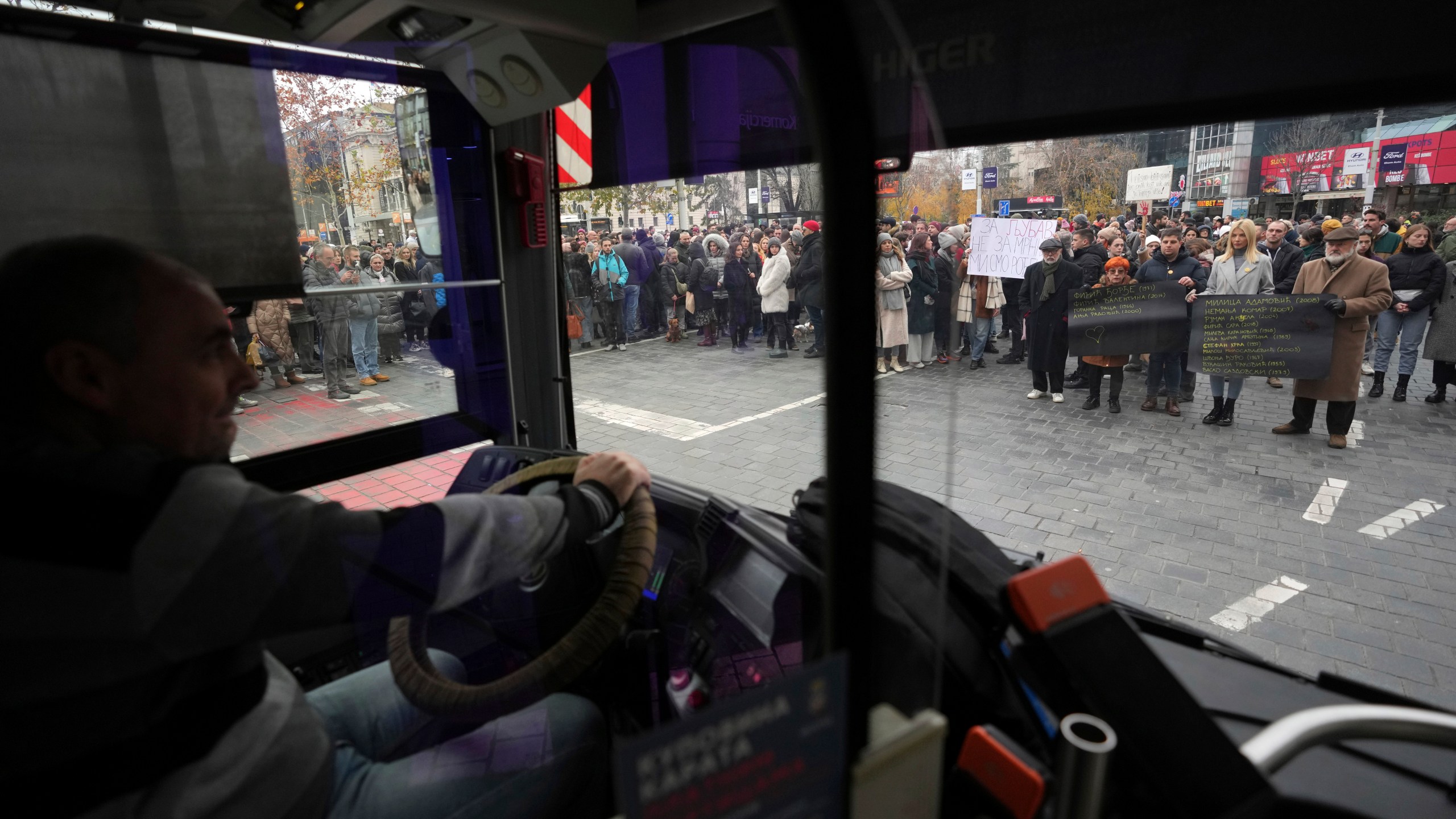 People stopping traffic stand in silence to commemorate the 15 victims of a railway roof collapse six weeks ago, demand accountability for the tragedy, in Belgrade, Serbia, Friday, Dec. 13, 2024. (AP Photo/Darko Vojinovic)