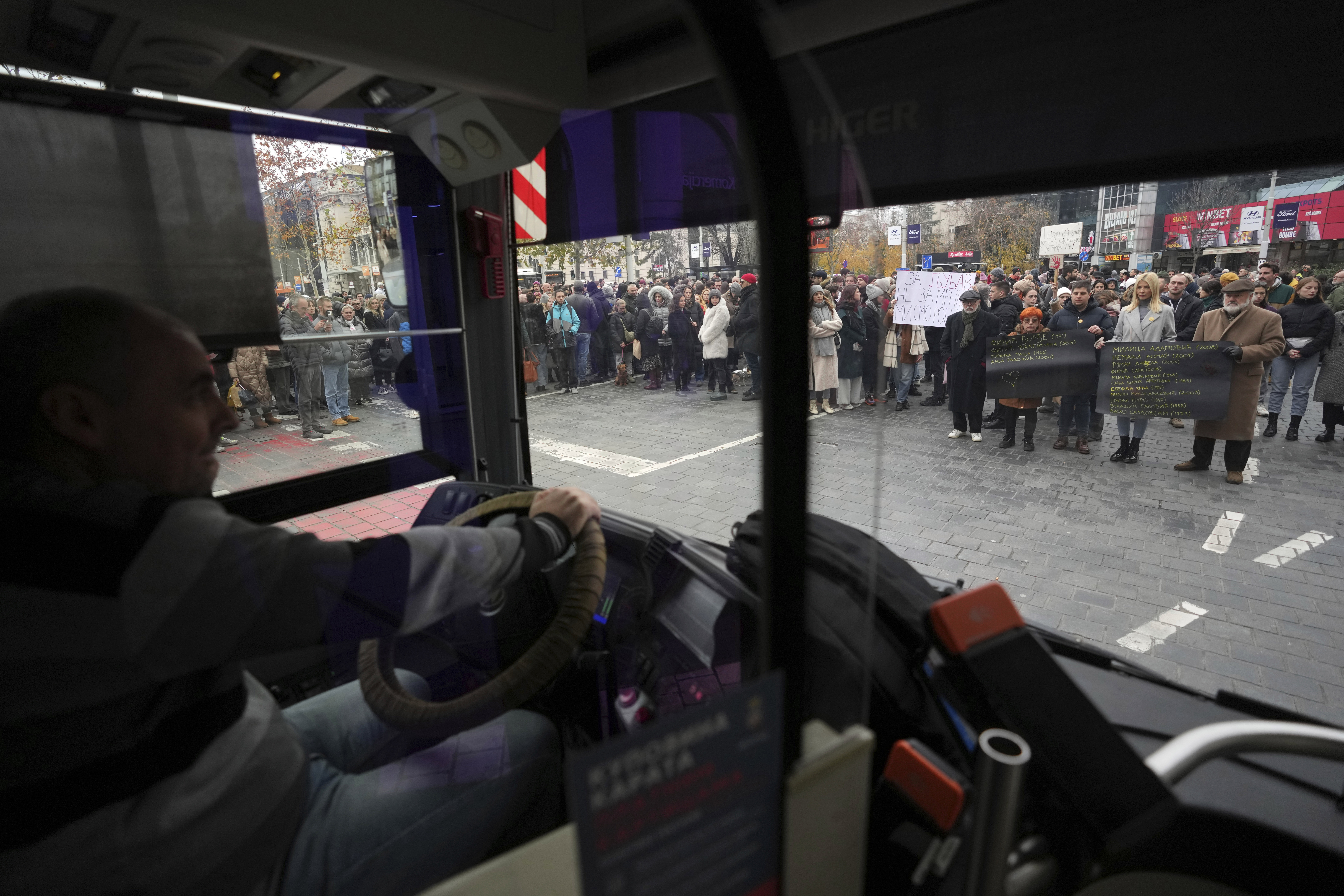 People stopping traffic stand in silence to commemorate the 15 victims of a railway roof collapse six weeks ago, demand accountability for the tragedy, in Belgrade, Serbia, Friday, Dec. 13, 2024. (AP Photo/Darko Vojinovic)