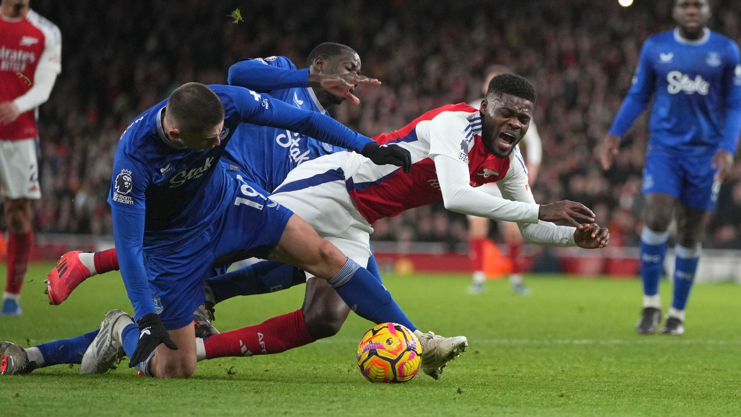 Arsenal's Thomas Partey, centre, challenges for the ball with Everton's Vitaliy Mykolenko during the English Premier League soccer match between Arsenal and Everton at Emirates Stadium in London, Saturday, Dec. 14, 2024. (AP Photo/Kin Cheung)