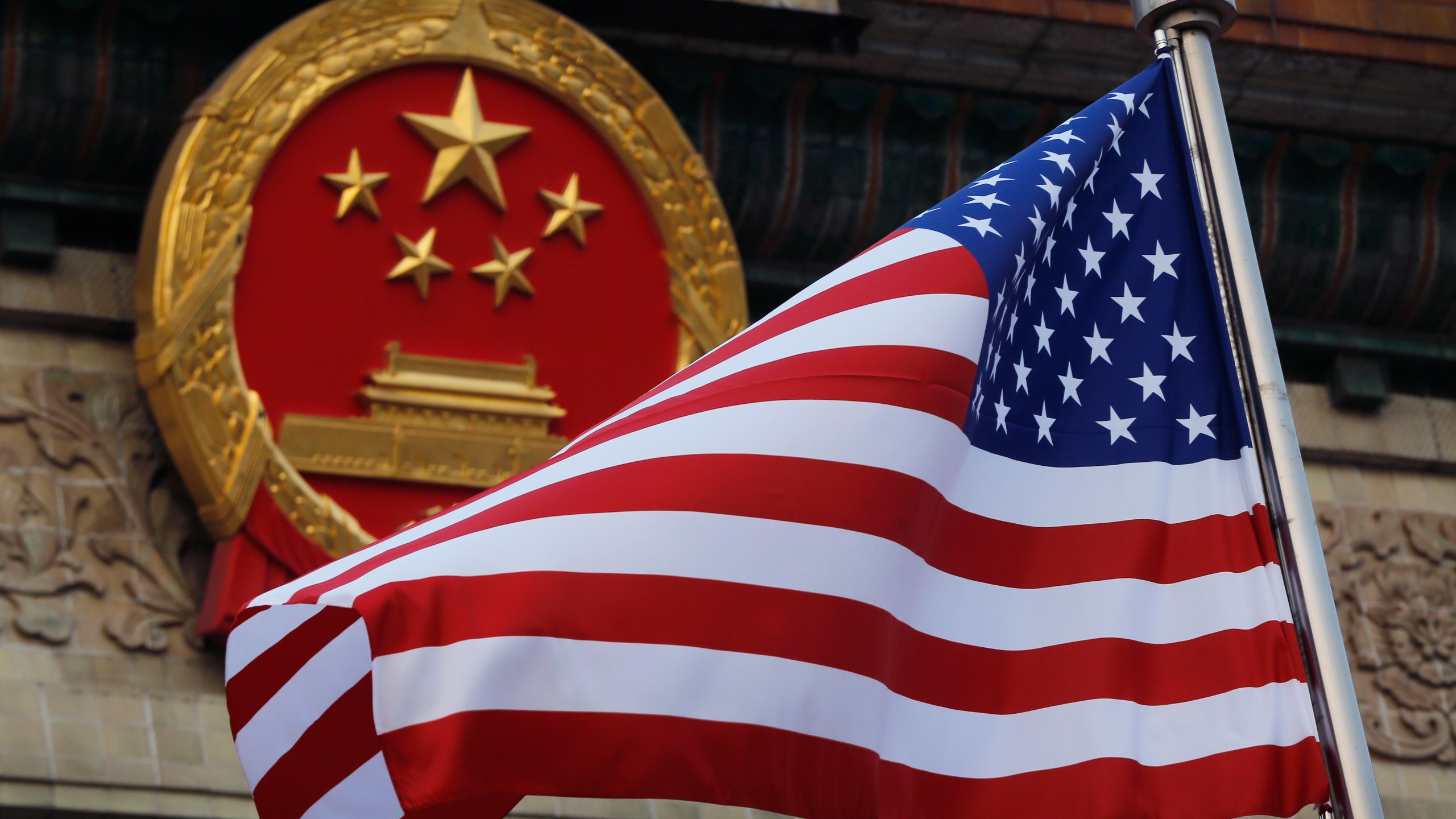 FILE - An American flag is flown next to the Chinese national emblem outside the Great Hall of the People in Beijing, Nov. 9, 2017. (AP Photo/Andy Wong, File)