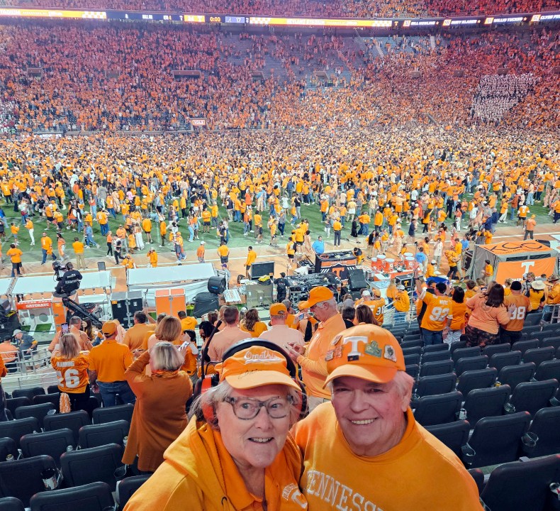 In this image provided by Earl Brown, Brown and his wife Judy pose as Tennessee fans storm the field after the Volunteers defeated Alabama in an NCAA college football game, Saturday, Oct. 19, 2024, in Knoxville, Tenn. (Earl Brown via AP)