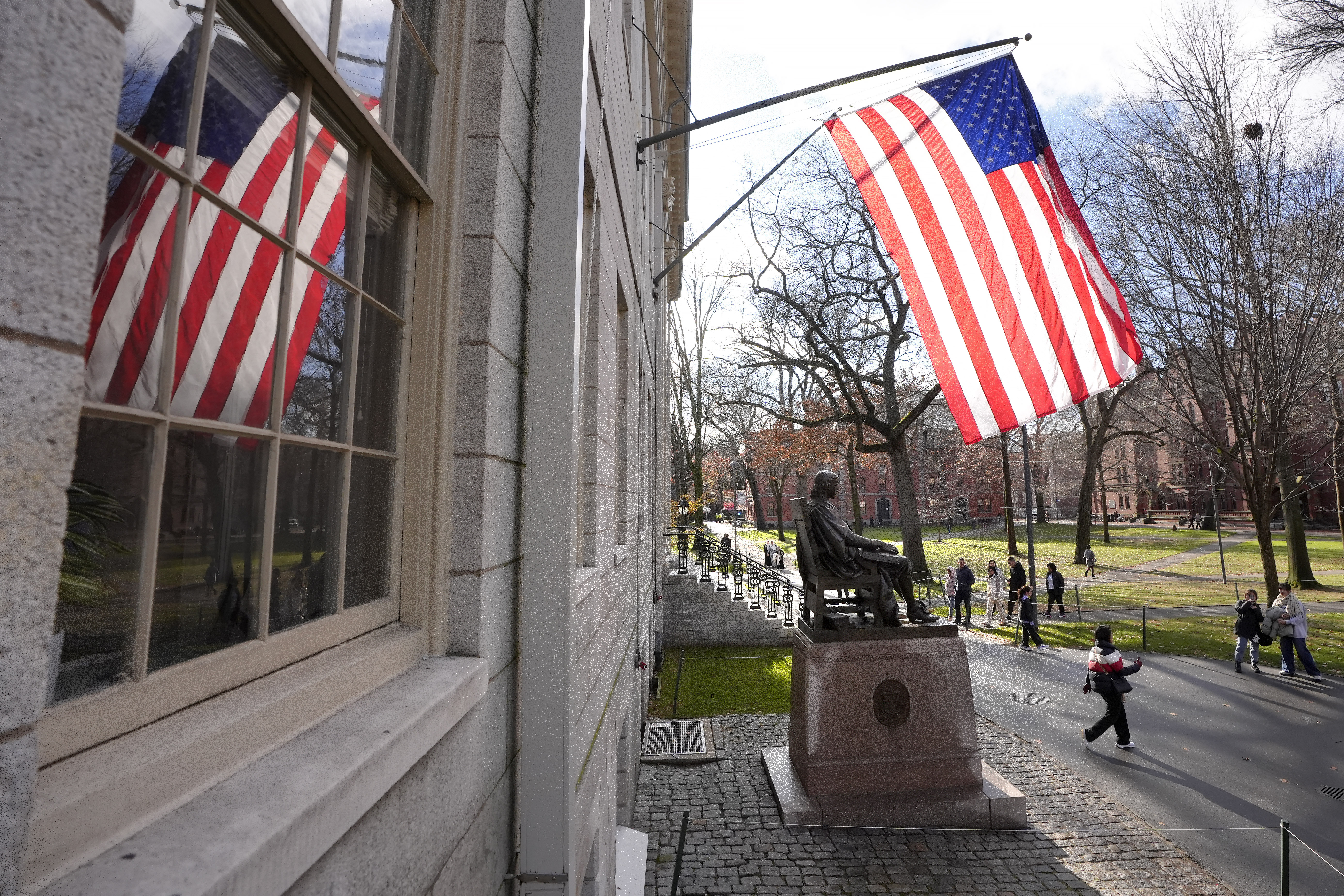 People walk past the John Harvard statue in Harvard Yard, Tuesday, Dec. 17, 2024, on the campus of Harvard University in Cambridge, Mass. (AP Photo/Steven Senne)