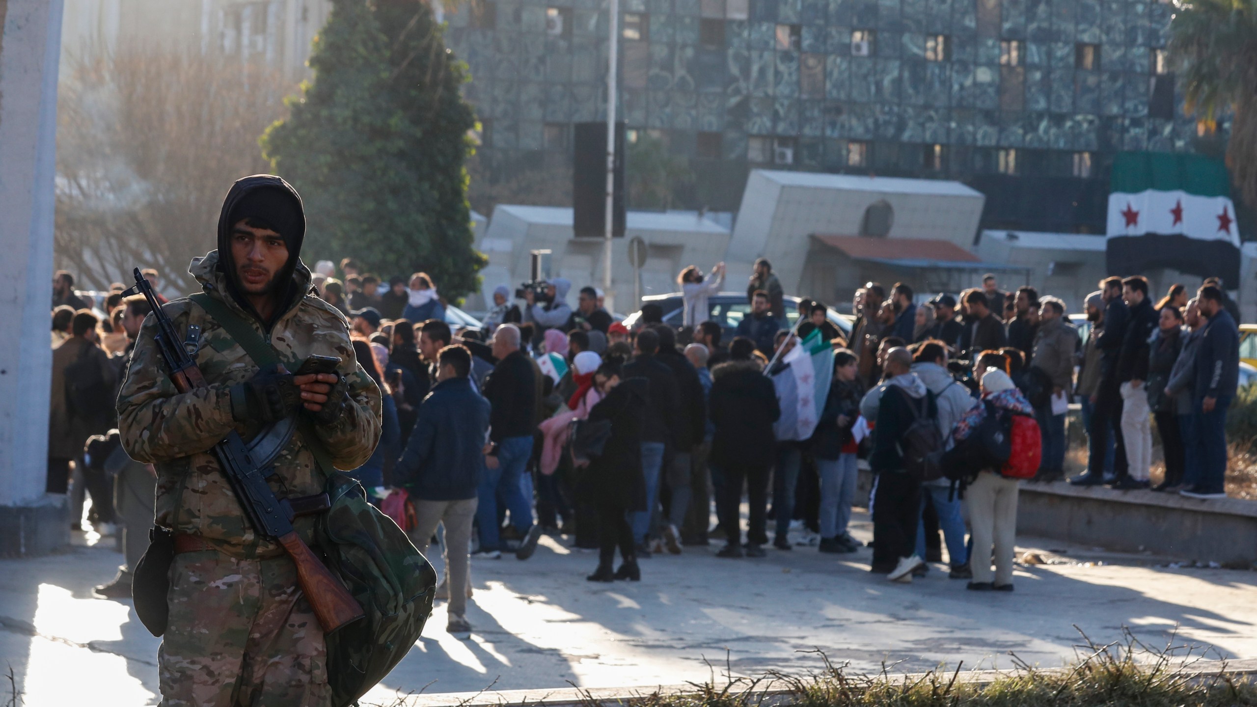 A Syrian fighter stands guard as activists gather at the Umayyad square during a protest to demand a secular state, in Damascus, Syria, Thursday, Dec. 19, 2024. (AP Photo/Omar Sanadiki)