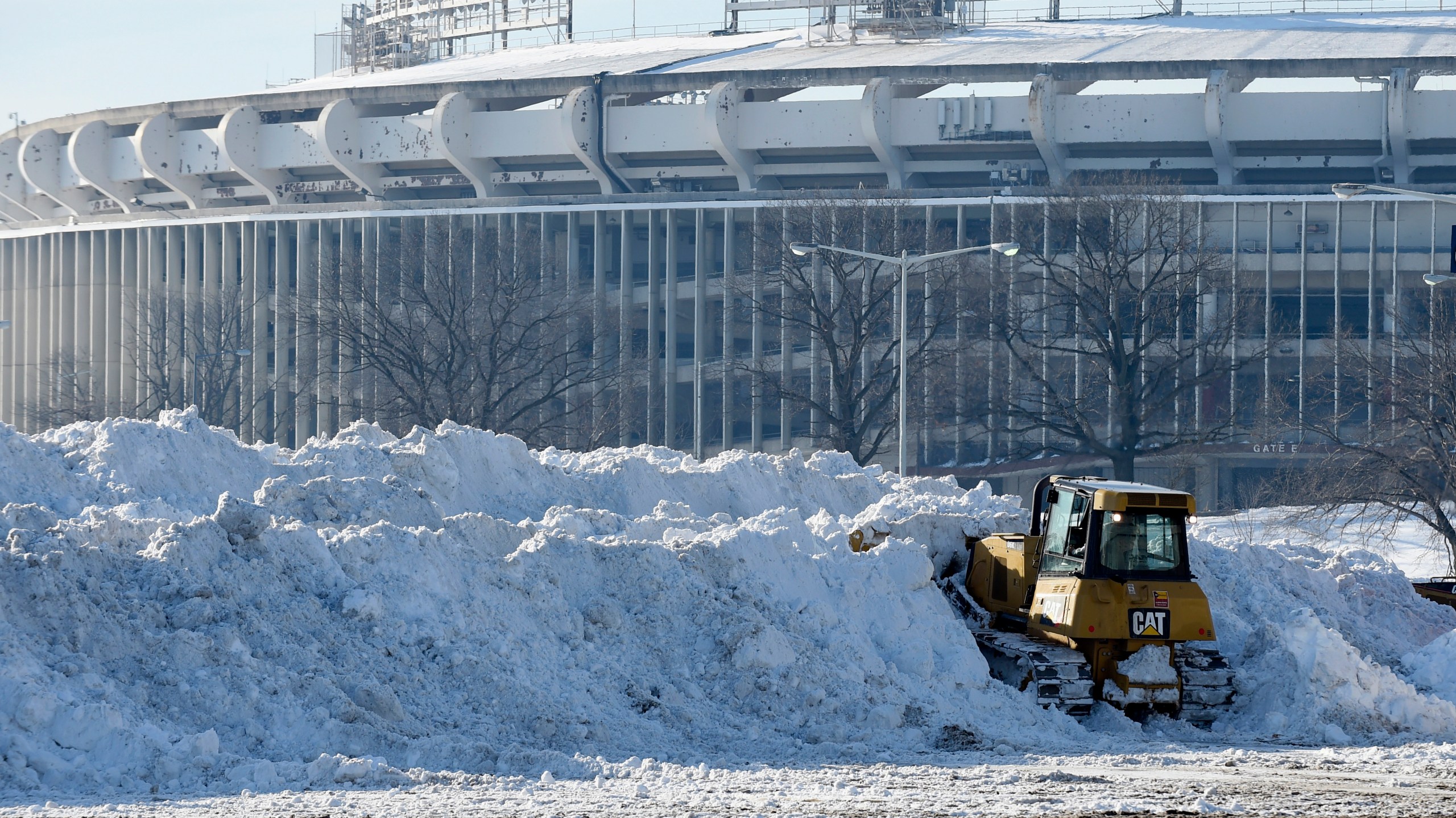 FILE - A vehicle pushes up pikes of snow after trucks dump their loads of snow in the parking lots of RFK Stadium in Washington, Monday, Jan. 25, 2016. (AP Photo/Susan Walsh, File)