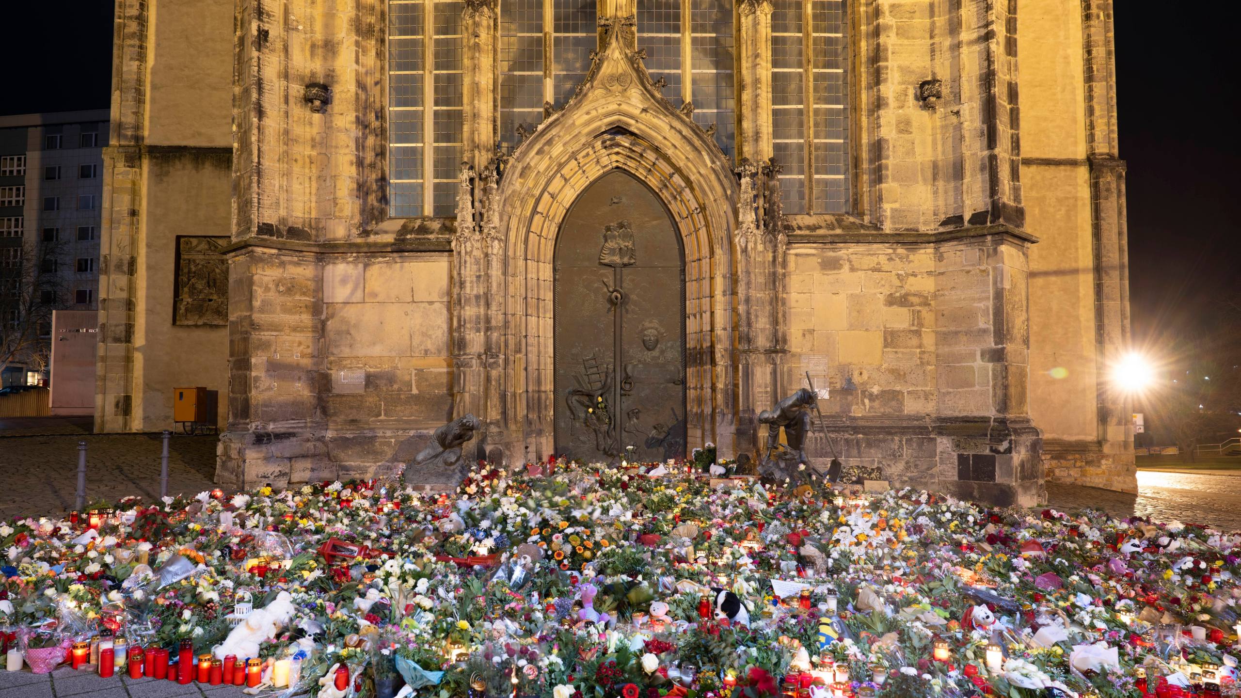 Candles, flowers and wreaths sit in front of the entrance to St. John's Church early Sunday, Dec. 22, 2024, in Magdeburg, Germany, after a car drove into a crowd at a Christmas market on Friday, Dec. 20. (Sebastian Kahnert/dpa via AP)